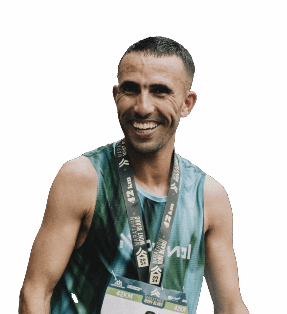 Smiling man wearing a medal after a race, wearing a marathon shirt with the text 42 km.