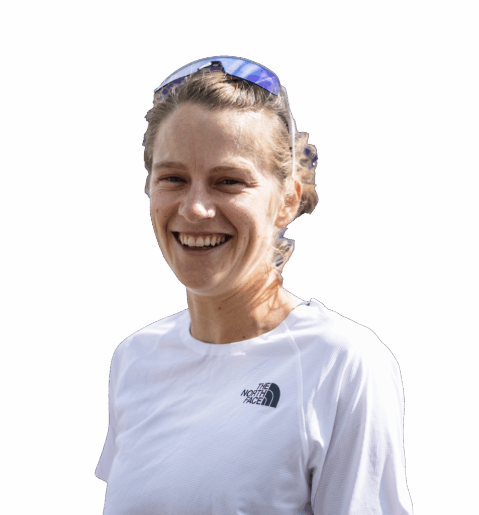 A smiling woman wearing a white sports outfit and sunglasses on her head, with a purple background.