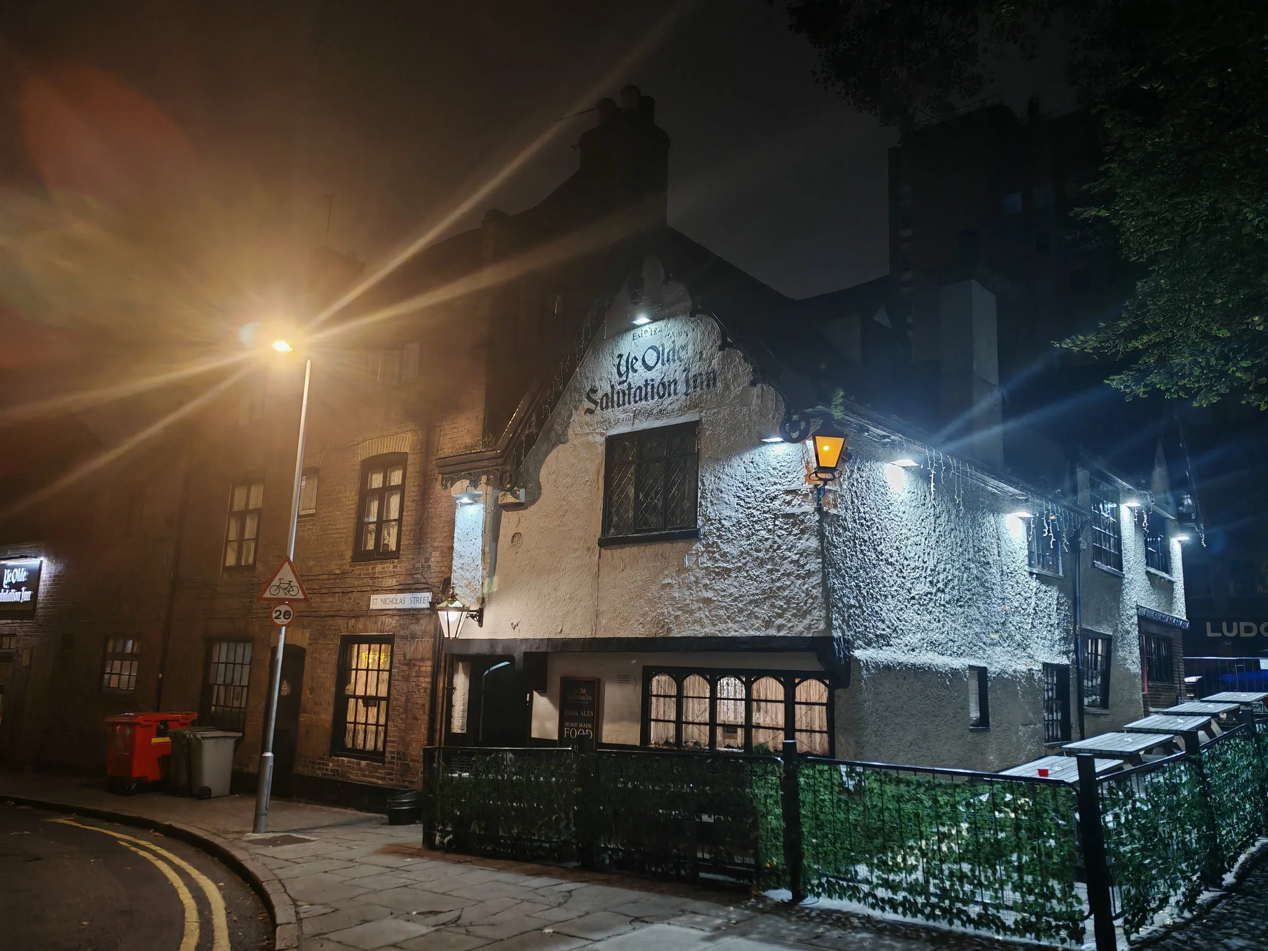 The Old Salutation Inn pub on St. Nicholas Street at night, with illuminated historic stone buildings and outdoor seating.