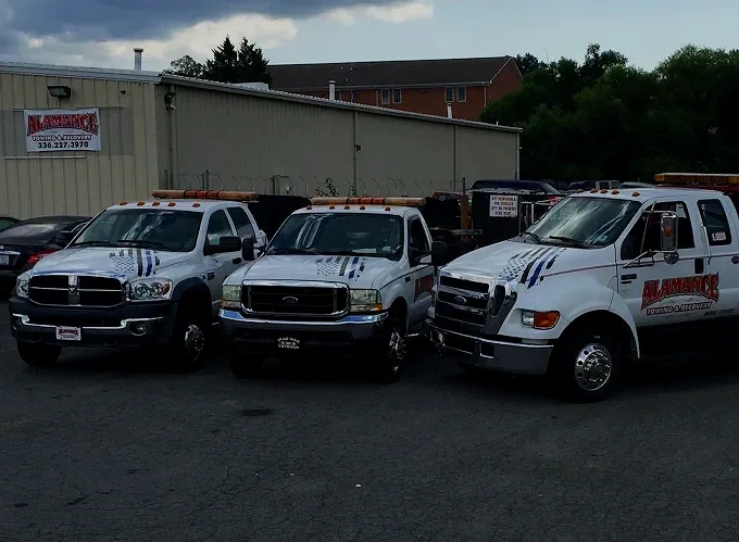 Three white utility trucks parked outside next to a building with a sign for Alarmance Security Services.