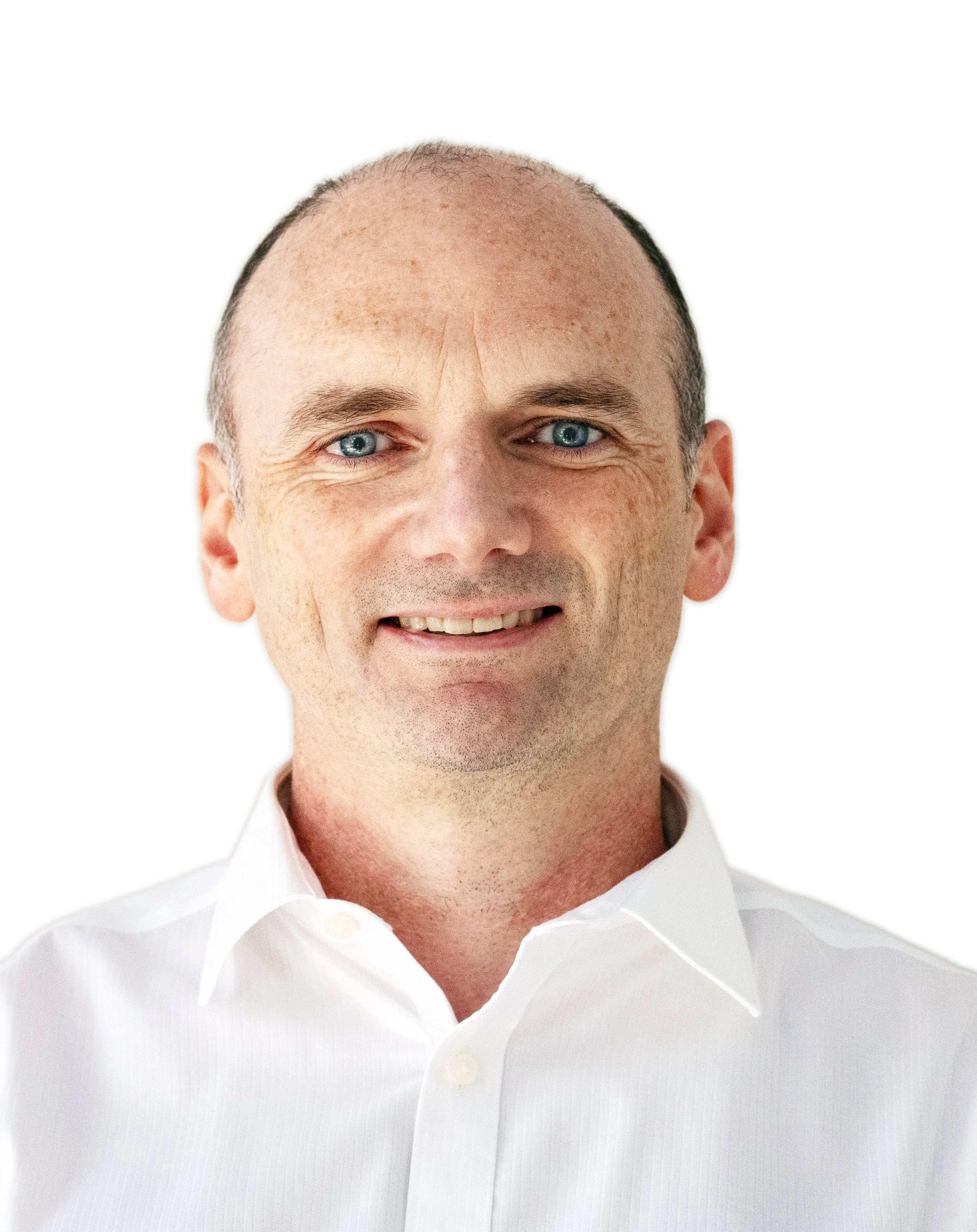 Headshot of a middle-aged man with blue eyes, short light brown hair, wearing a white collared shirt, smiling against a plain white background.