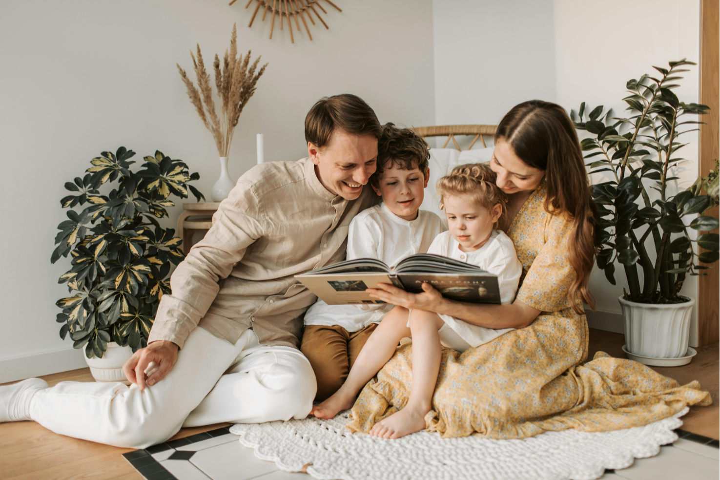 Famille assise dans un salon lumineux aux tons beiges et naturels, partageant un moment paisible. Une ambiance douce et harmonieuse qui reflète le bien-être intérieur cher à Studio Vertige.