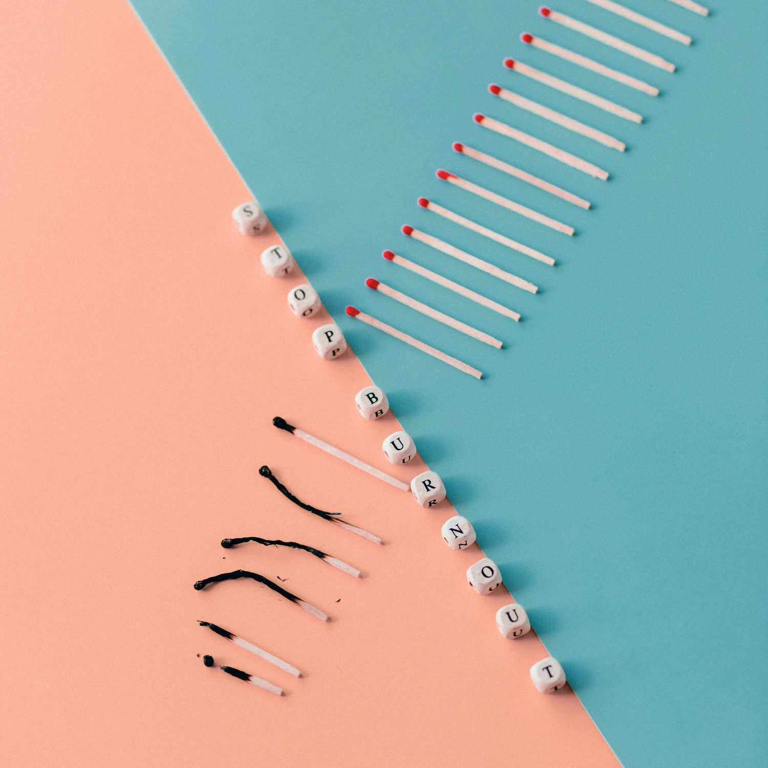 Matches and lettered beads spelling out 'STOP BURNOUT' on pink and blue background, with black and white matchstick heads.