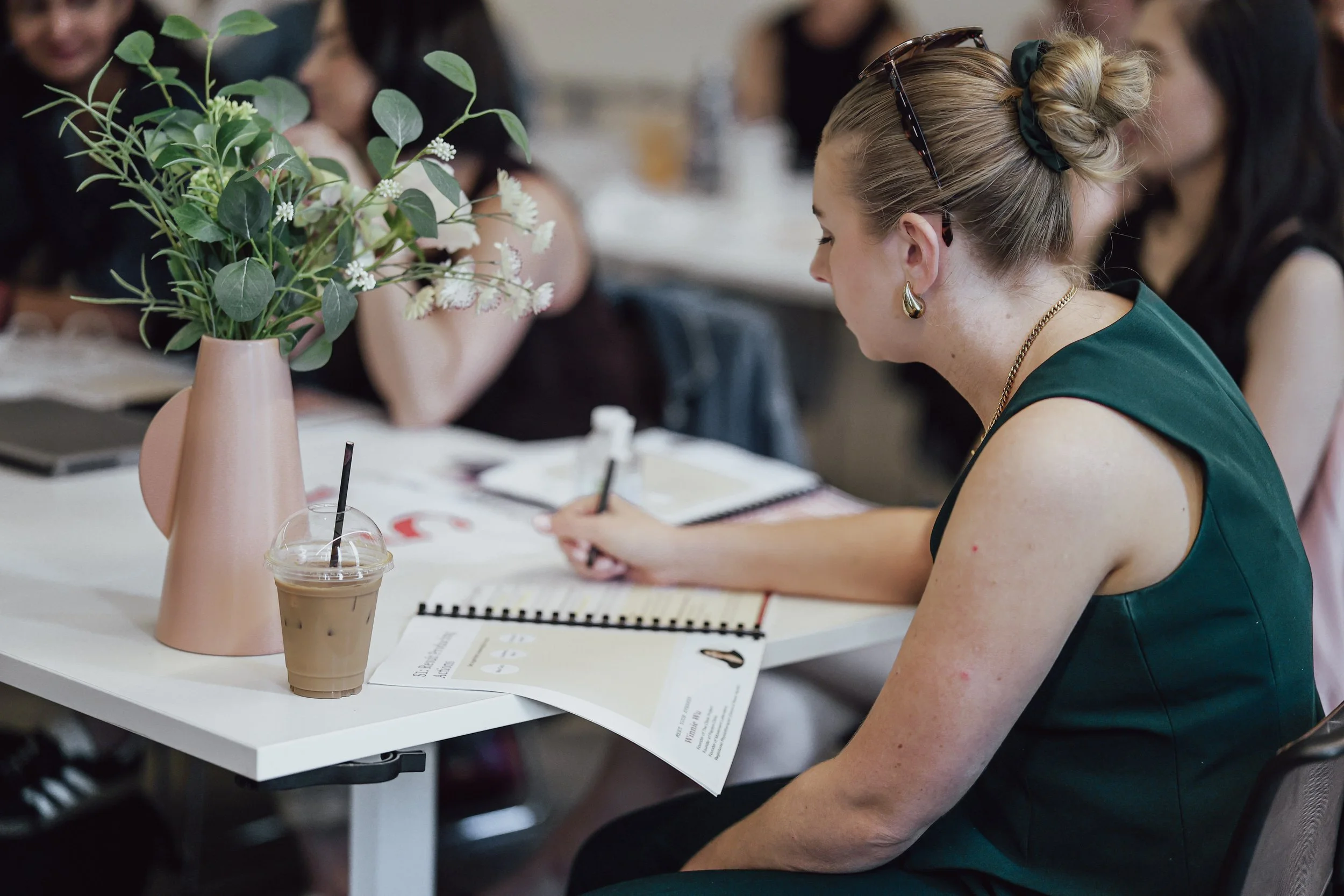 Person sitting and writing notes in a notebook, with handwritten notes and diagrams on the pages.