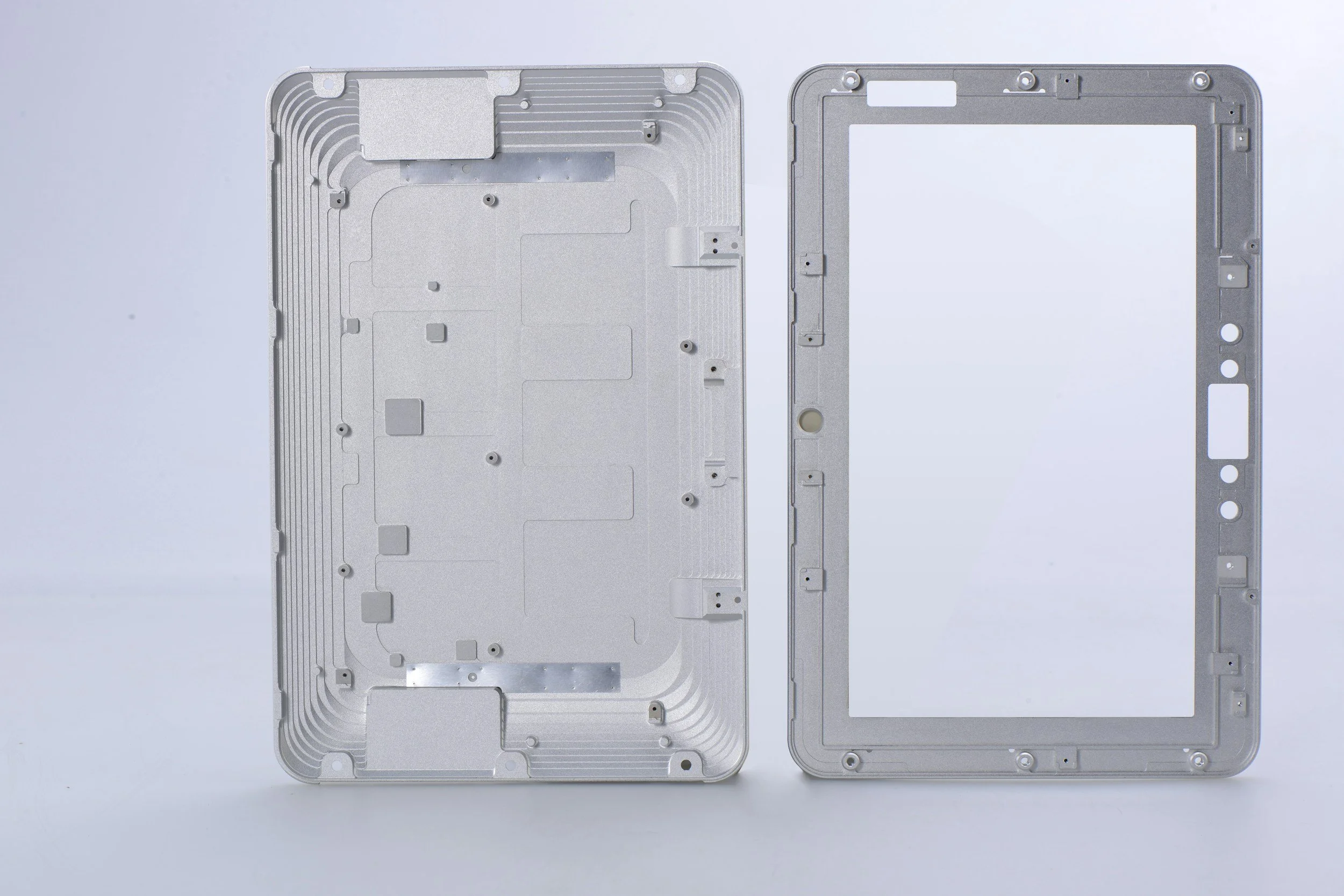 Partes metálicas de un dispositivo electrónico, probablemente una carcasa o una estructura interna, colocadas sobre un fondo blanco.