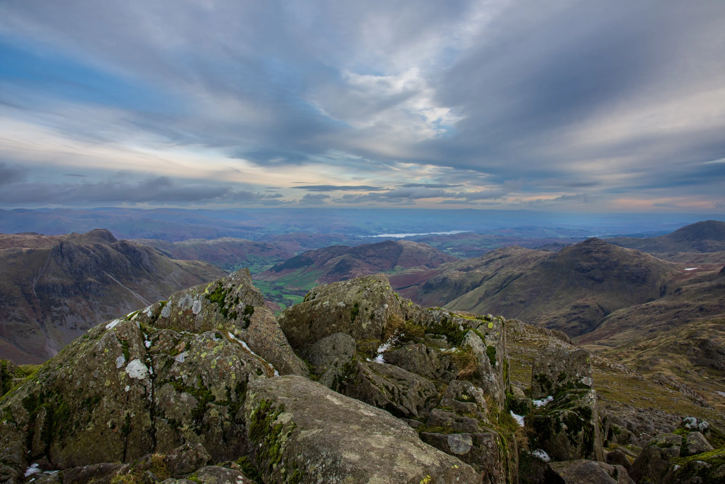 The rocky summit of Bowfell in the Lake District, looking over Langdale, towards Windermere, under an Autumn sky