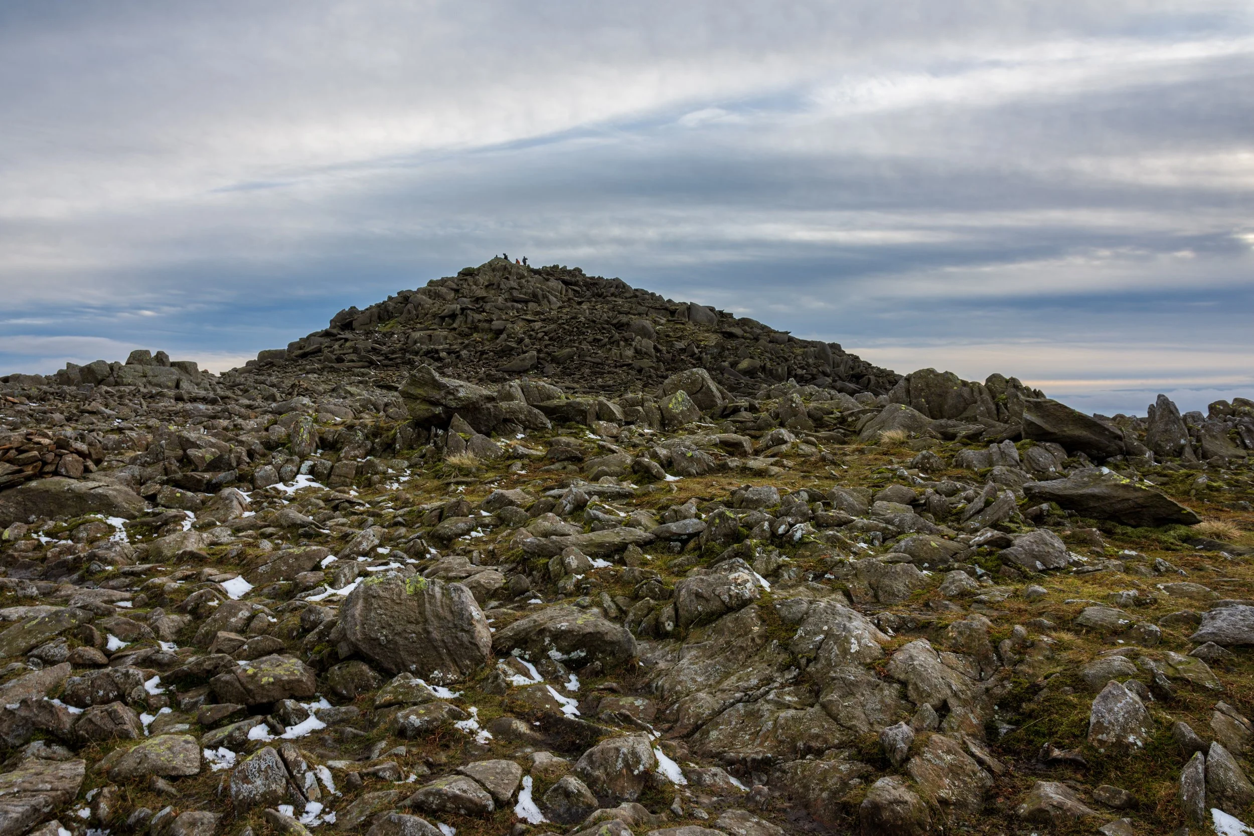The approach to the rocky summit of Bowfell in the Lake District, over a boulder field with snow in the crevices