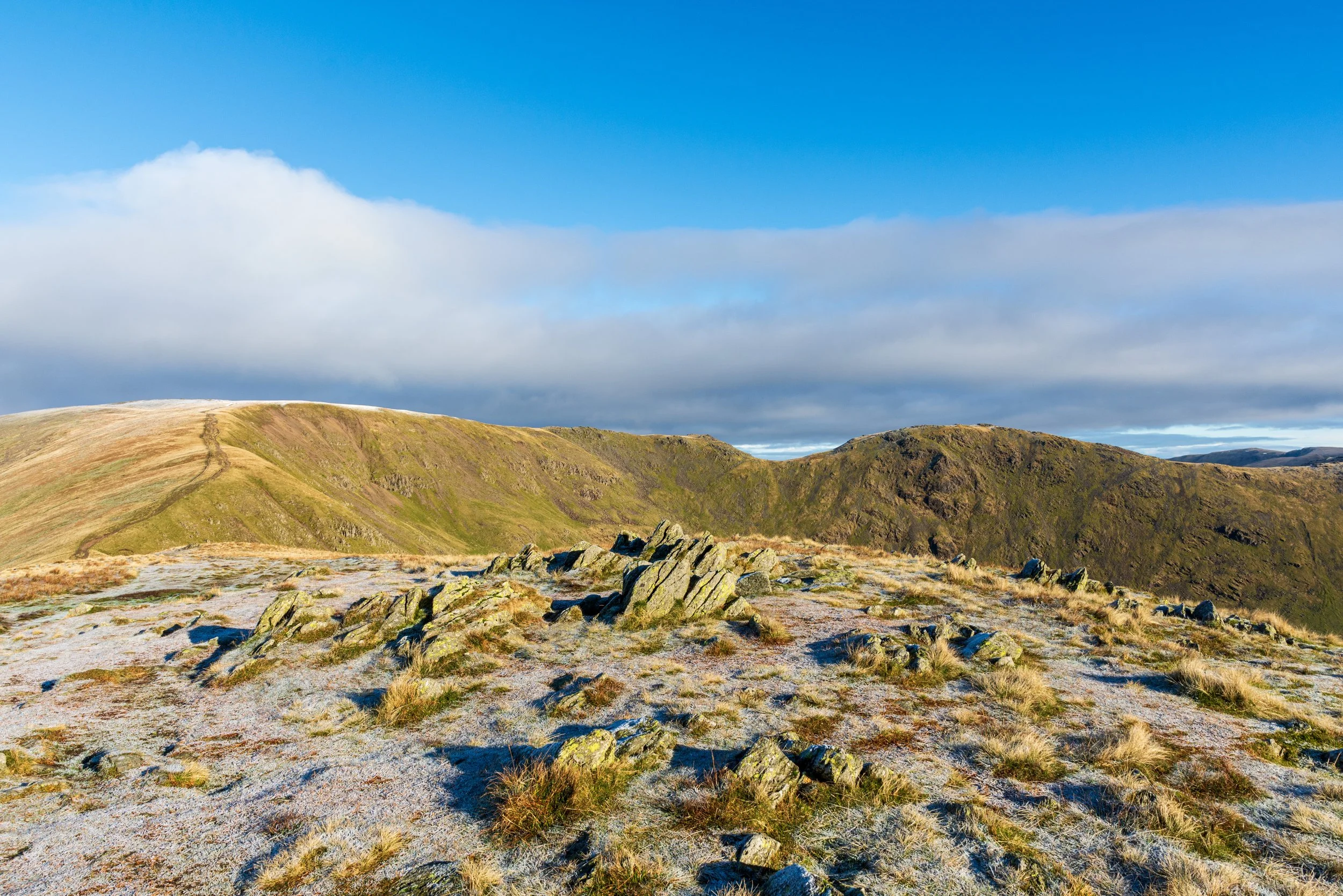 A view of a frost-capped Fairfield in the Lake District, on a sunny day, looking from Great Rigg, above Ambleside, and with Hart Crag to the right