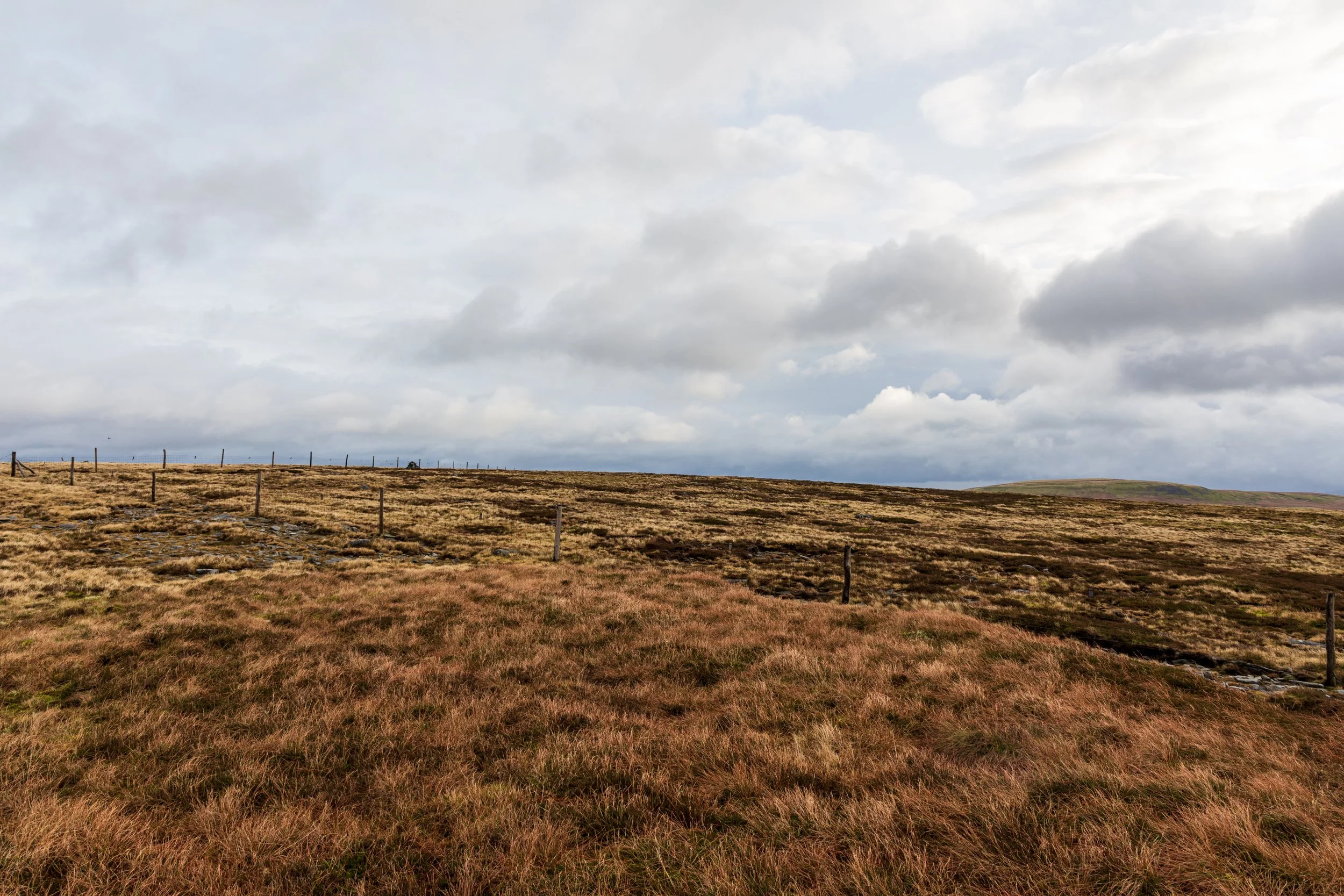 The summit of Little Shunner Fell, near Great Shunner Fell in the Yorkshire Dales, with Lovely Seat in the background. Open moorland, with heather, and a small cairn at the summit