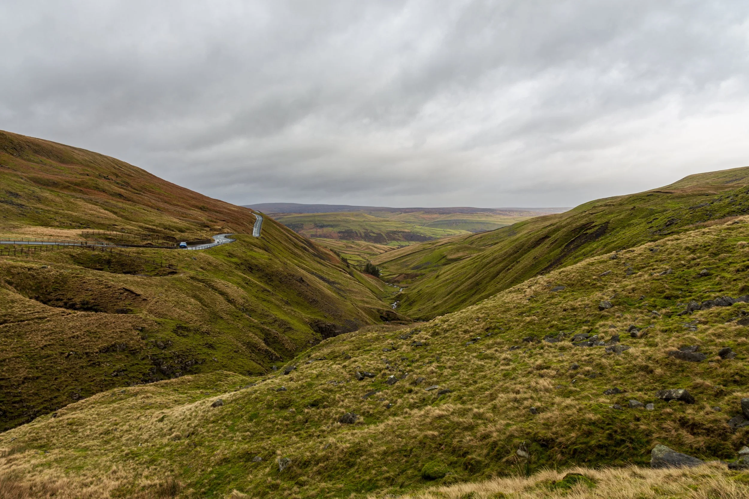 A view of the Butter Tubs pass between Muker and Hawes on a wet day, the road running alongside a valley with a stream, looking out towards Swaledale. View from the path running between Great Shunner Fell and Lovely Seat in the Yorkshire Dales