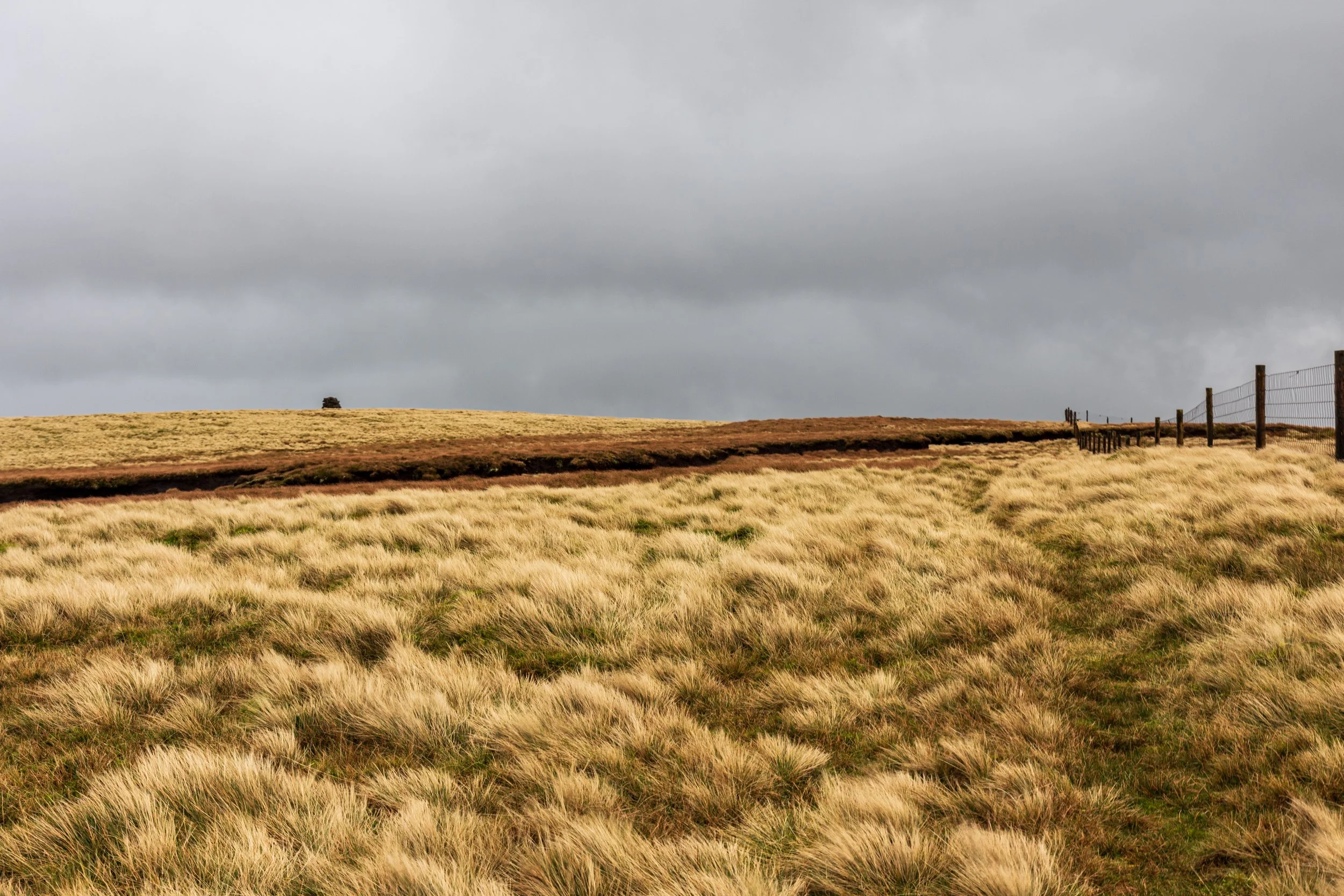 Open moorland and peat hags on the approach to the summit of Lovely Seat, with a stormy sky in the background, during a walk in the Yorkshire Dales