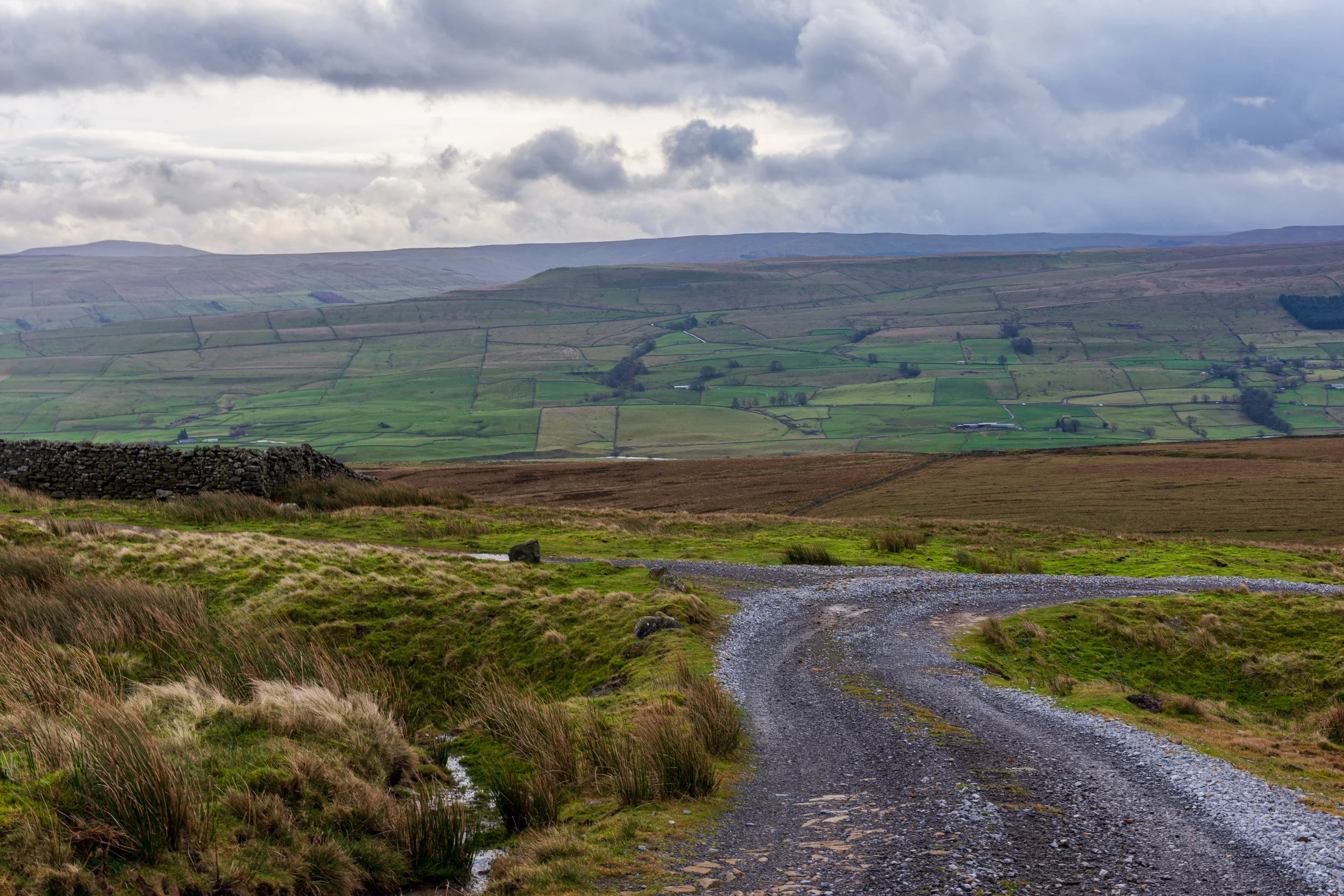 A fork in a track leading downhill from Lovely Seat, with the green hills of Wensleydale in the background