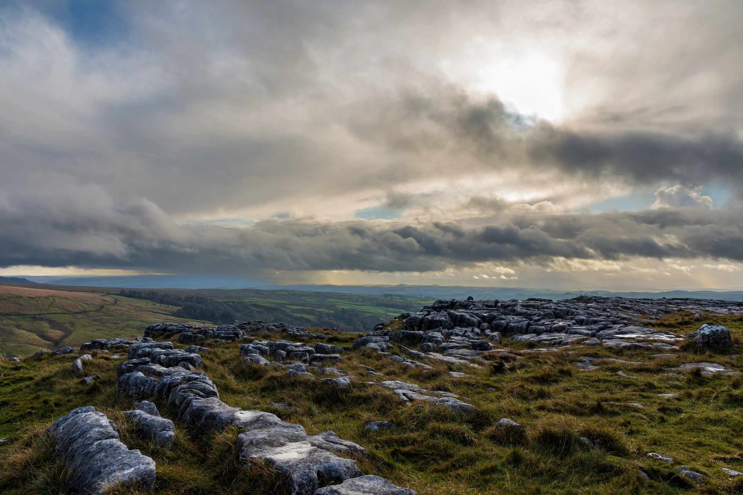 The limestone outcrops on top of New Close Knotts, looking across  Malhamdale with a moody sky filled with dramatic cloud formations