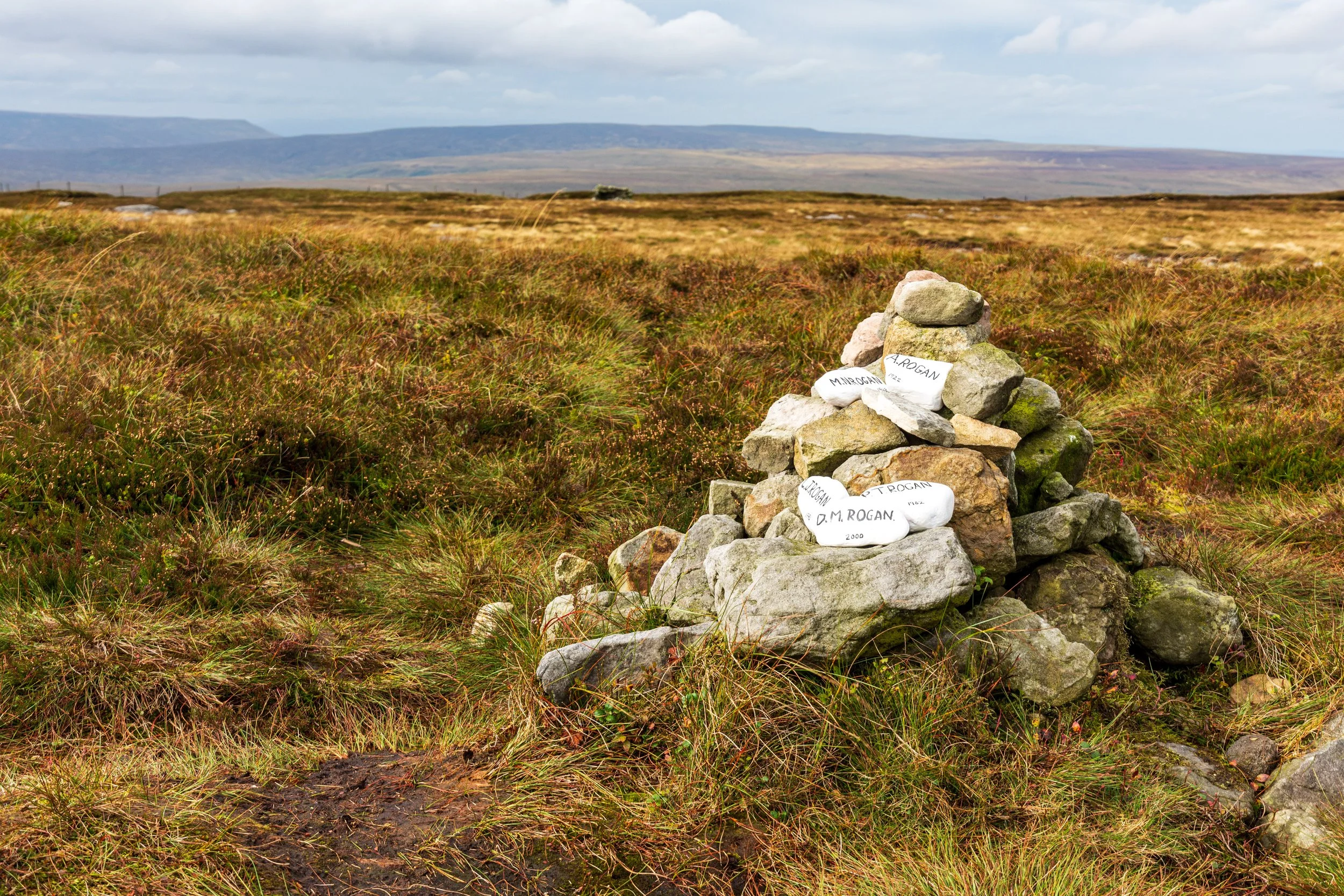 Small cairn on the wet moorland summit of Rogan's Seat in the Yorkshire Dales. Some stones are named by people in the Rogan family