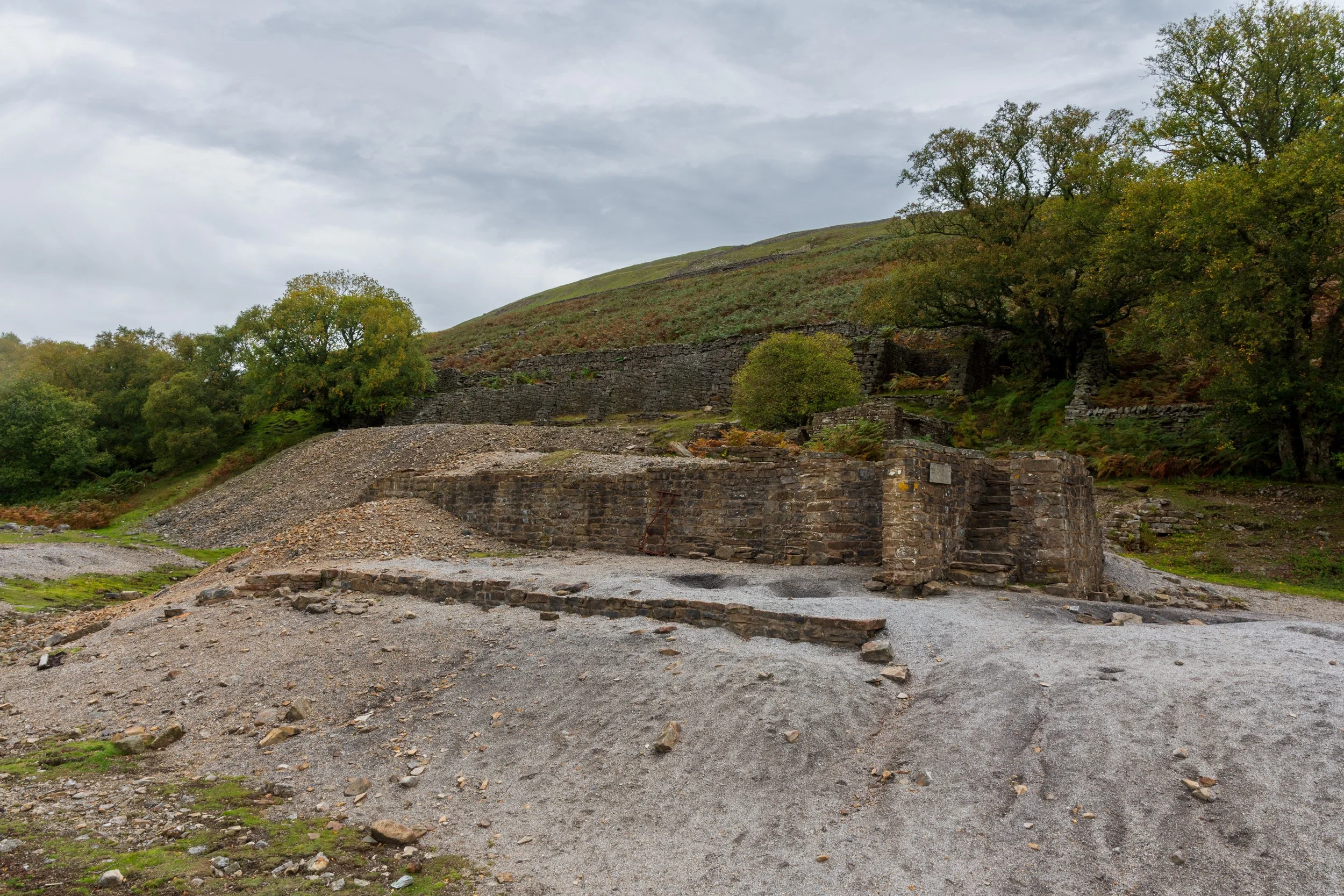 Remains of a lead mine building in Gunnerside Gill, near Rogan's Seat and Muker in Swaledale, built on a level, with a stone stairway to a demolished floor (with another level in the background.