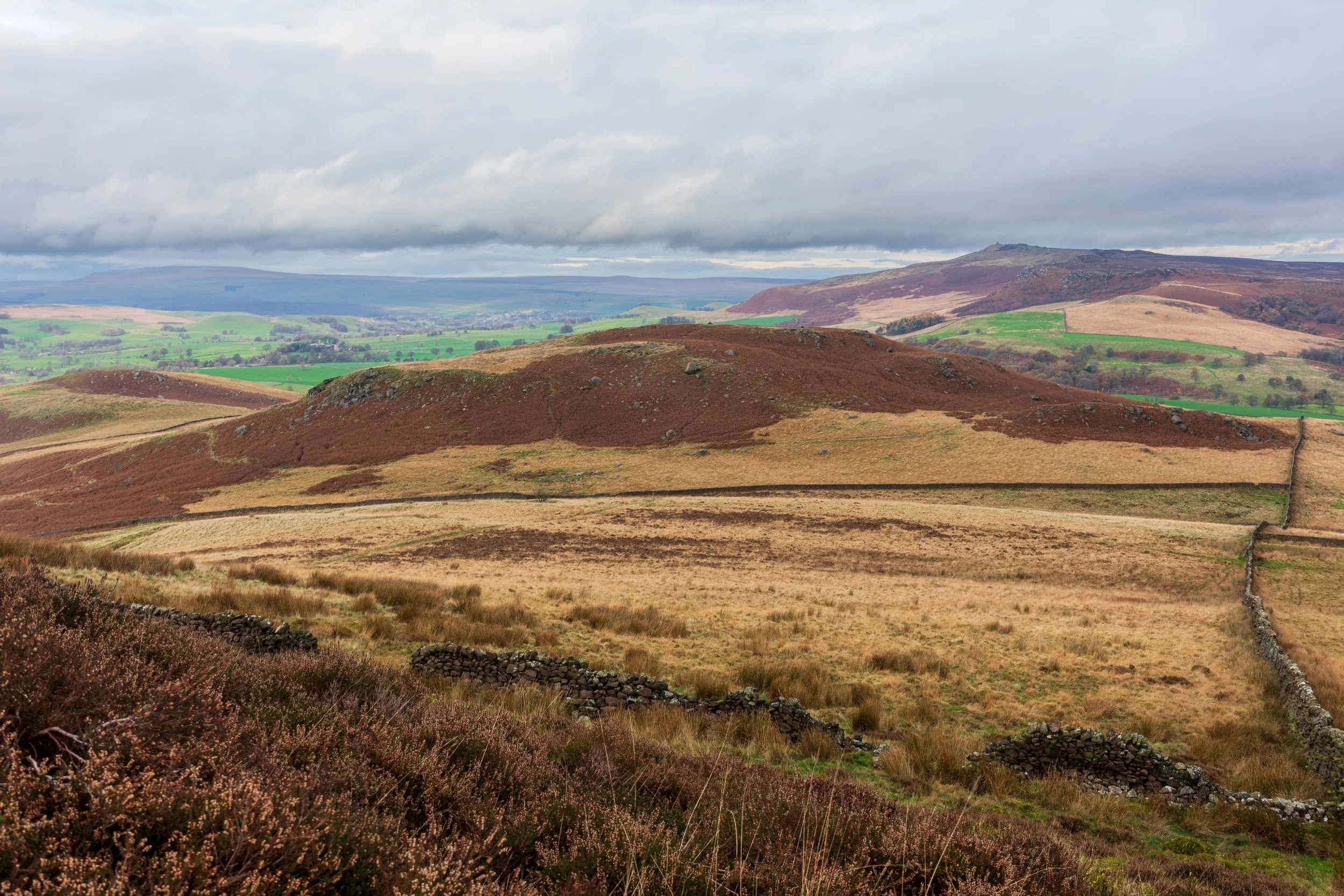 A view, looking down on Rough Haw from Sharp Haw, with Flasby Fell on the left, Cracoe fell and war memorial in the mid-ground (on the right) and Great Whernside and Meugher in the background