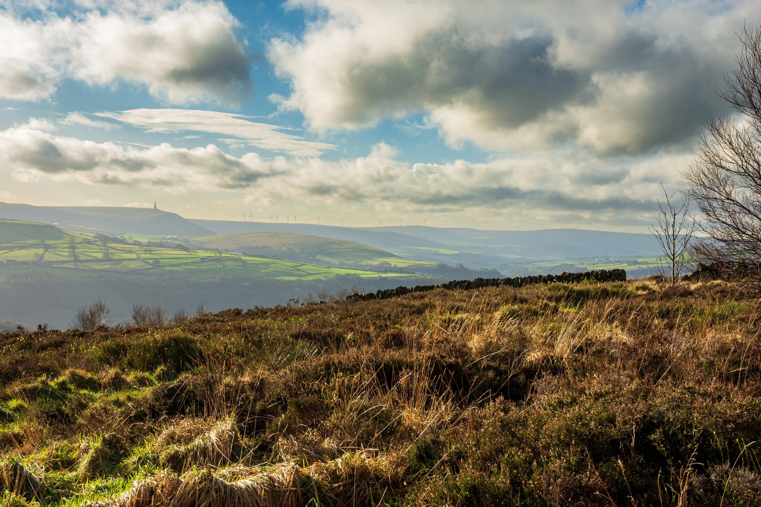 A views of Stoodley Pike from a moor near Hebden Bridge, on a calm sunny day, under broken clouds