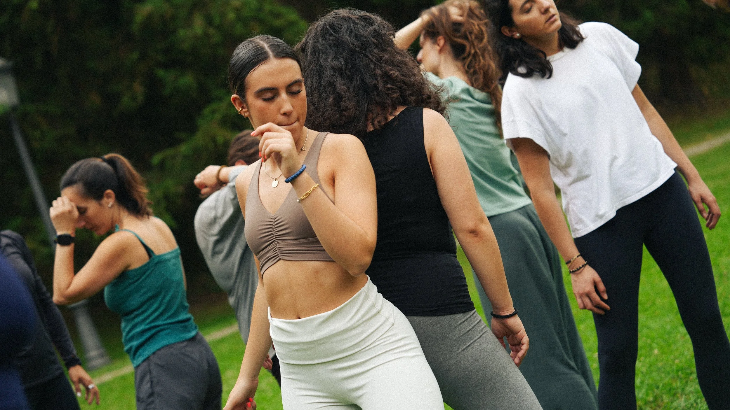 Grupo de mujeres practicando yoga en un parque al aire libre en un día soleado, en postura de equilibrio