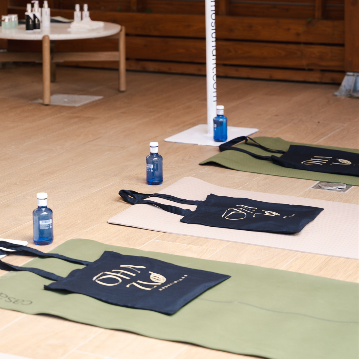 OHAZI EXPERIENCES: Esteras de yoga con bolsas y botellas de agua colocadas en un suelo de madera en una clase de yoga.