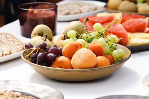 OHAZI EXPERIENCES: Vasija con uvas, duraznos, melón, y otras frutas junto a una vela y comida en el fondo.