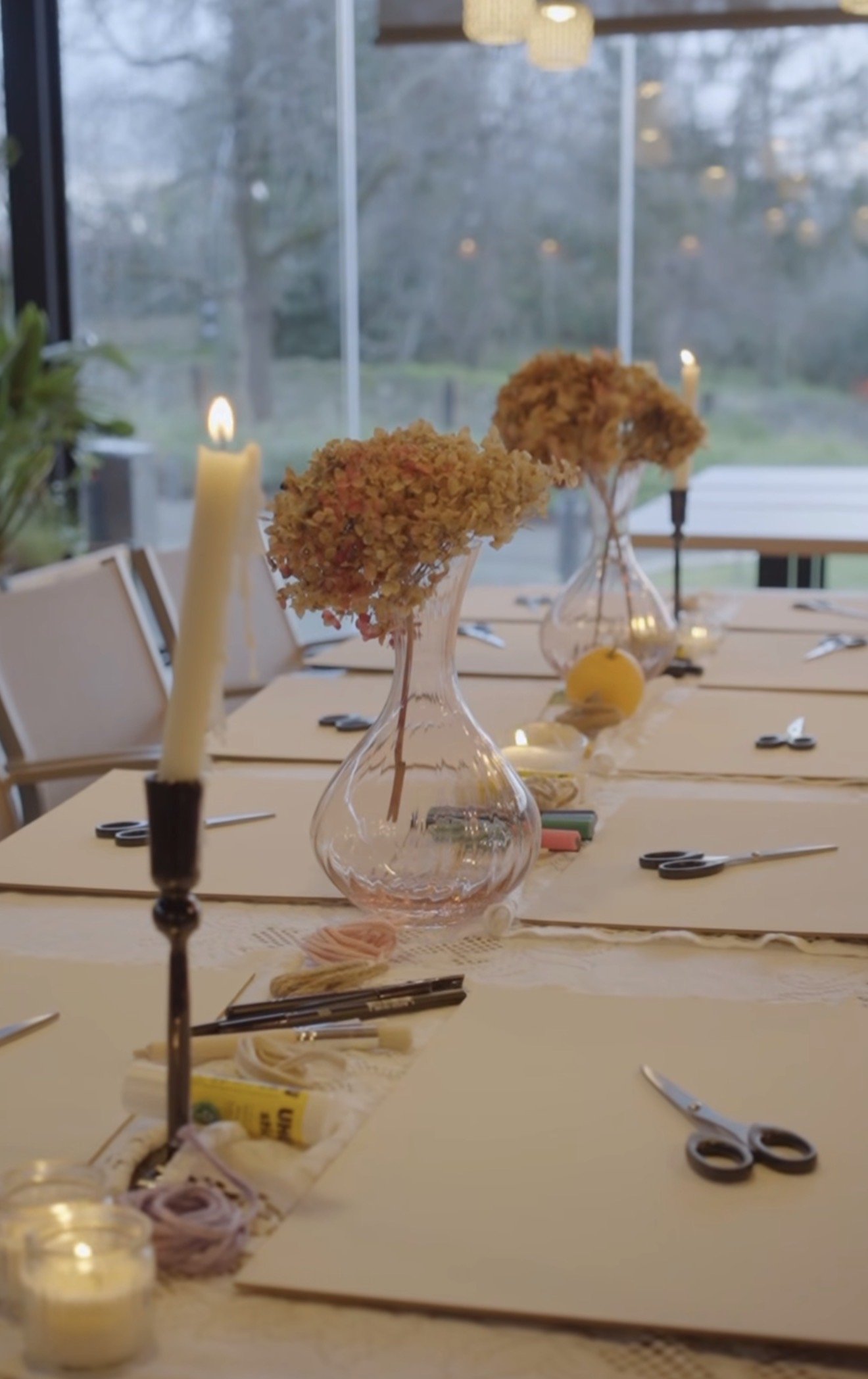 OHAZI EXPERIENCES: Mesa decorada con floreros con flores secas, candelabros con velas encendidas y utensilios de color negro, preparada para un evento o comida.