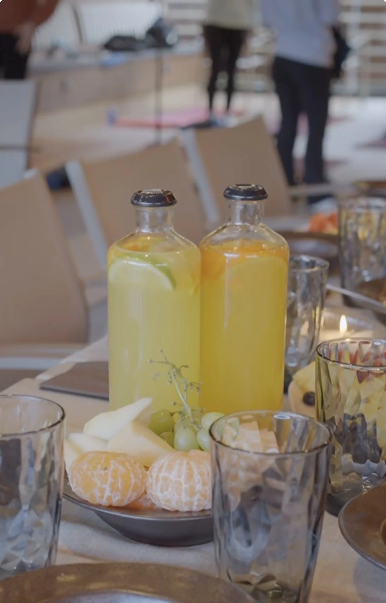 OHAZI EXPERIENCES: Botellas de jugo de limón y limón en la mesa, rodeadas de vasos y fruta en un ambiente de comedor.