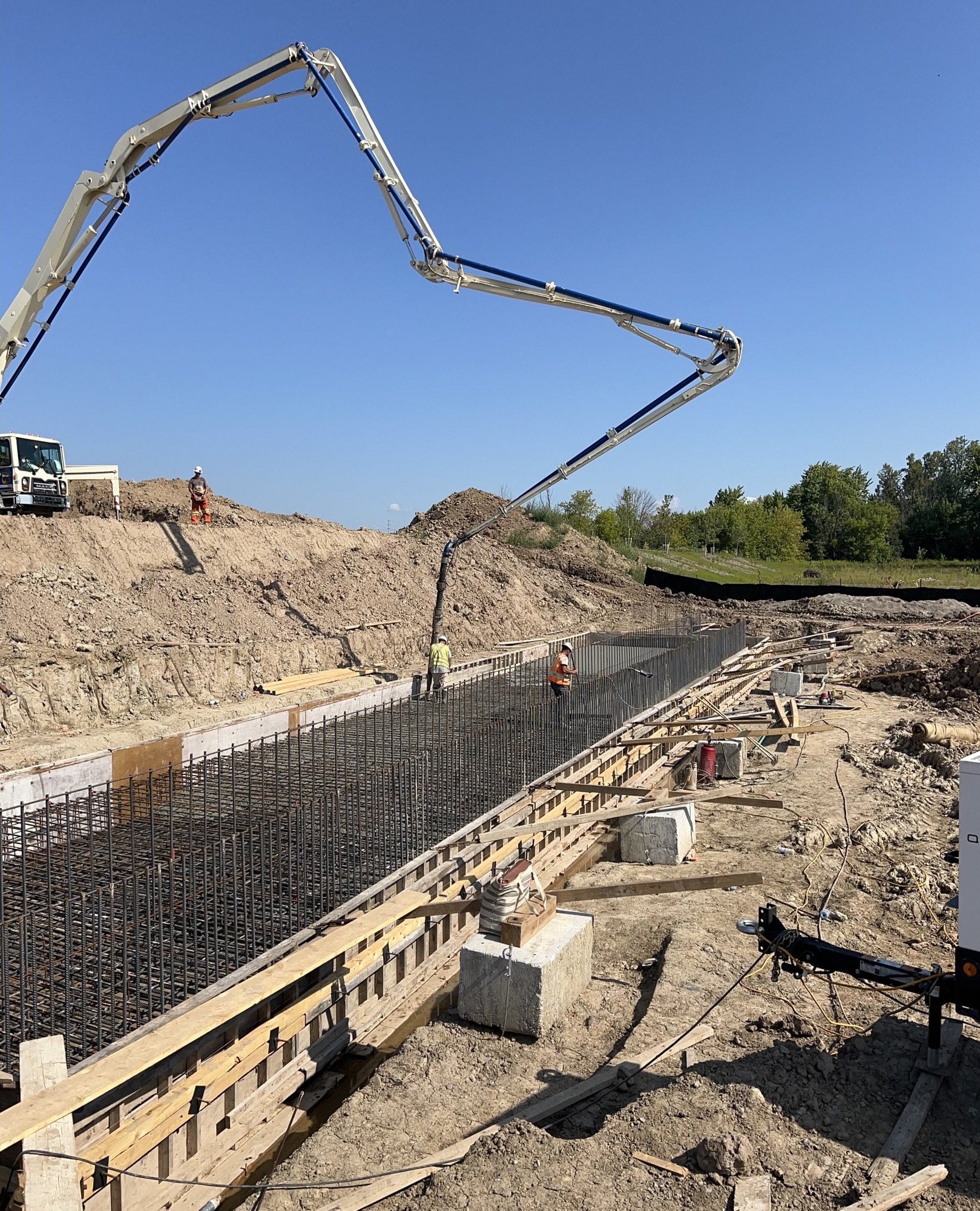 Construction workers building a concrete foundation with rebar reinforcement at a construction site on a sunny day.