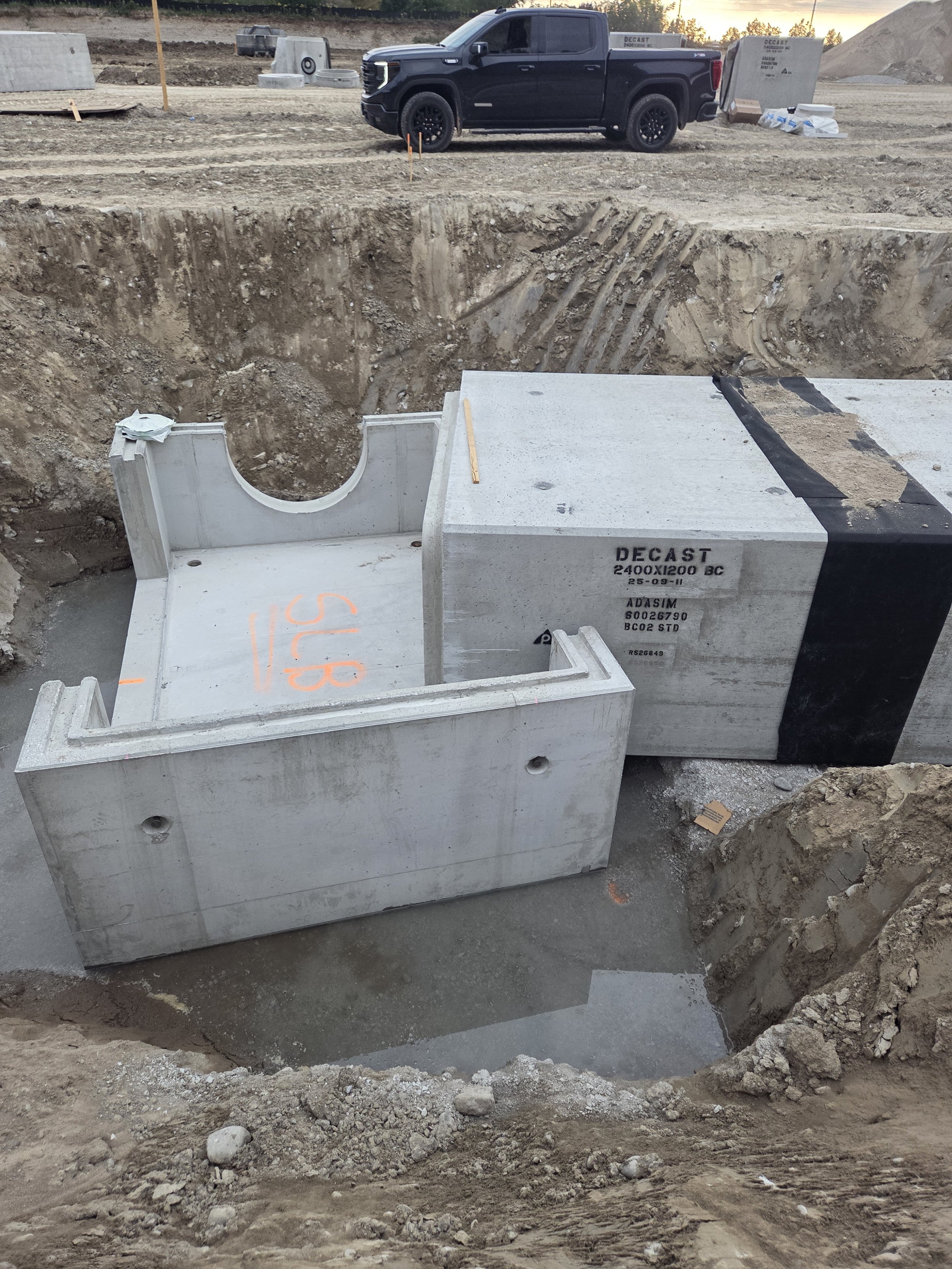 Construction site with concrete foundation blocks and a black pickup truck parked in the background.