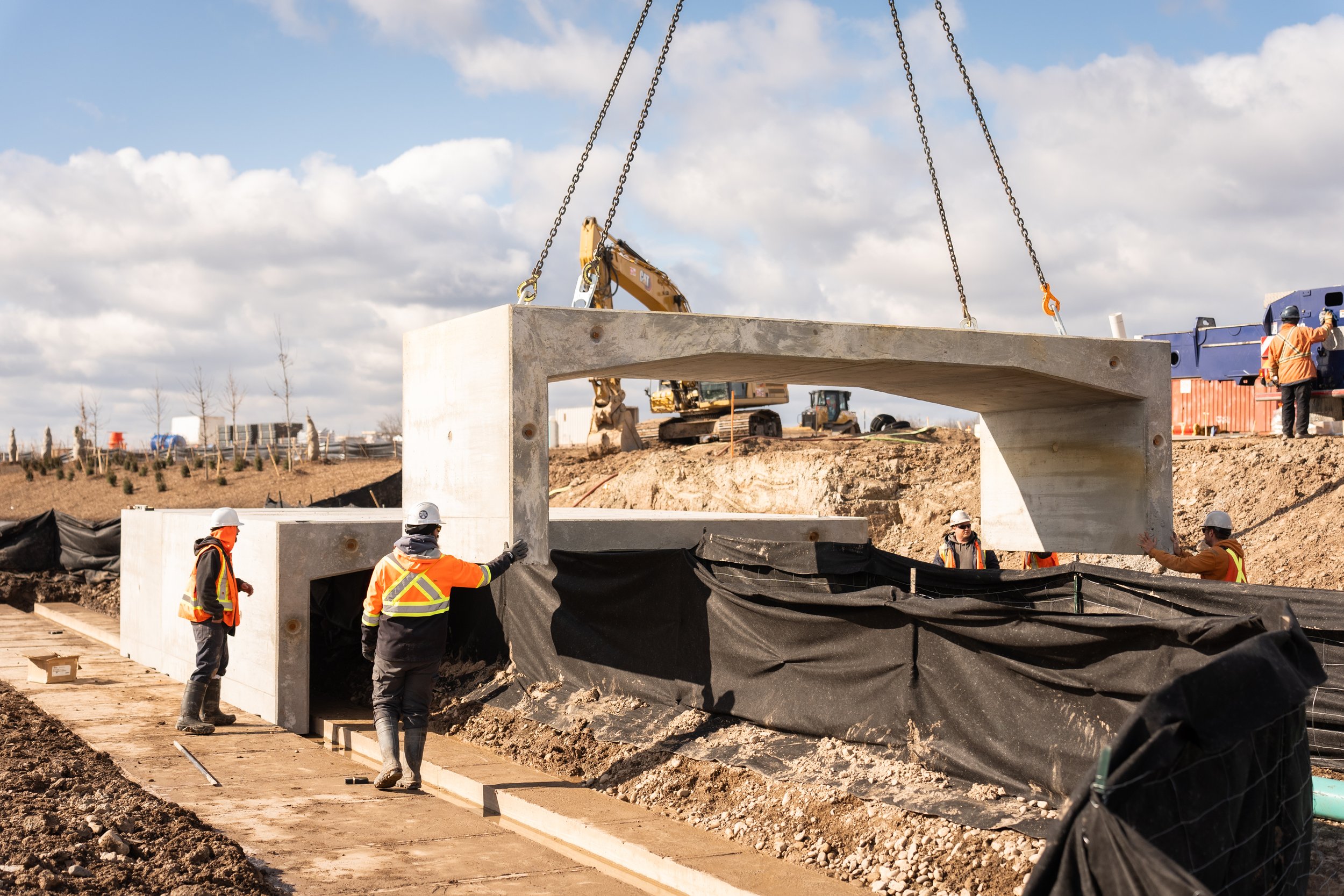 Construction workers installing a large concrete structure at a construction site.