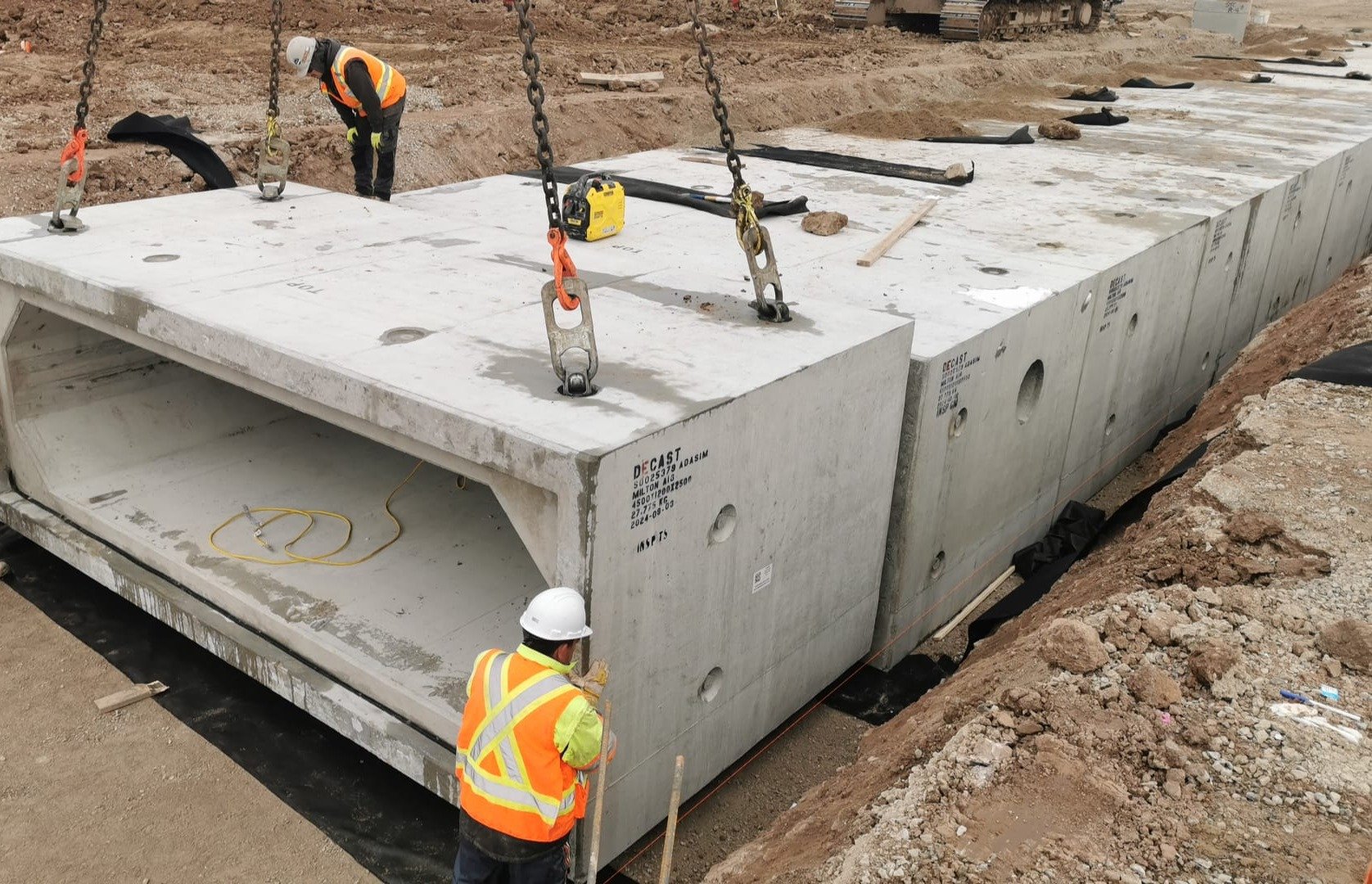 Construction workers installing precast concrete bridge beams at a construction site.