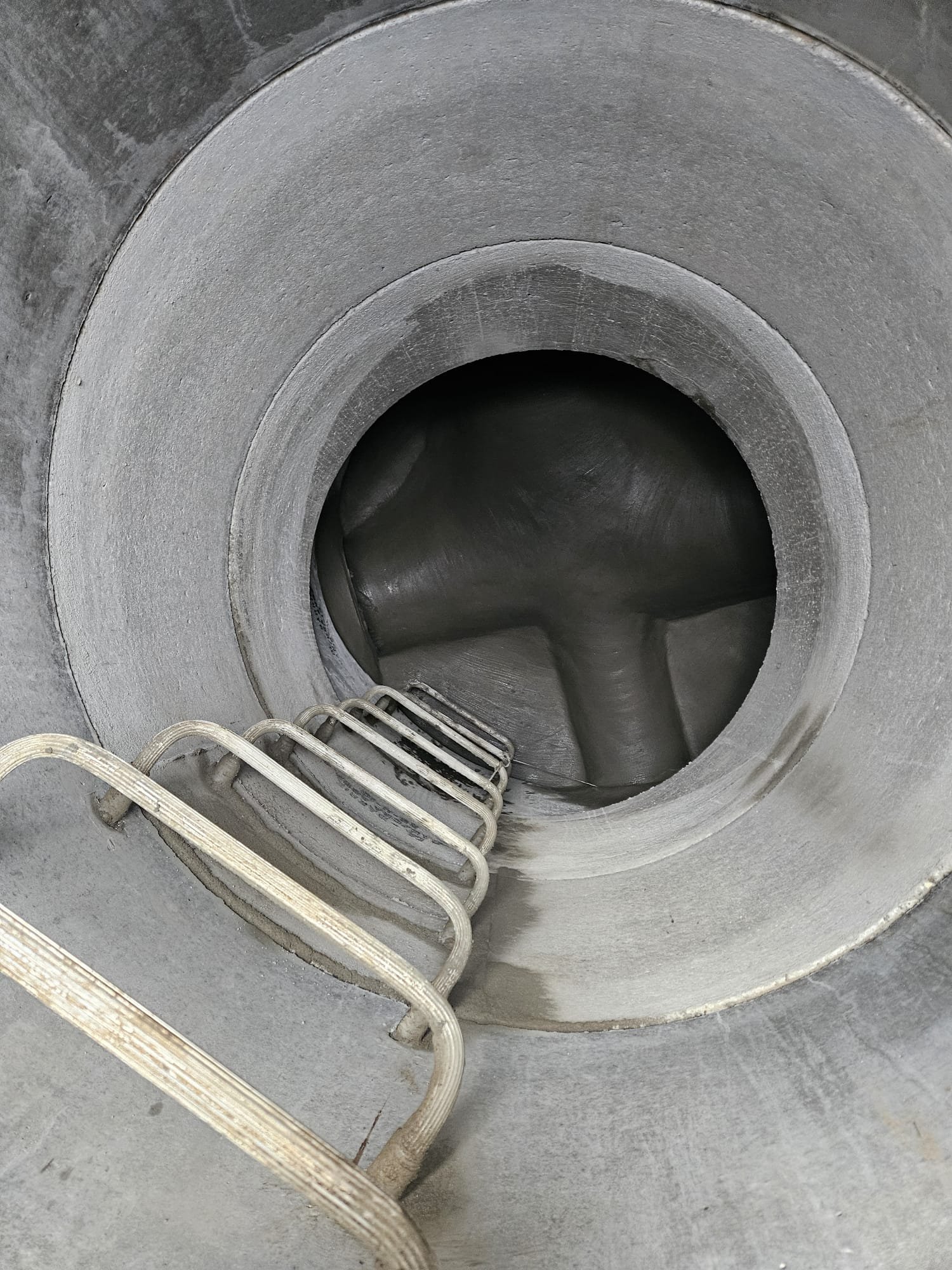 Inside a large industrial mixer or container with a metal staircase leading downward into it.