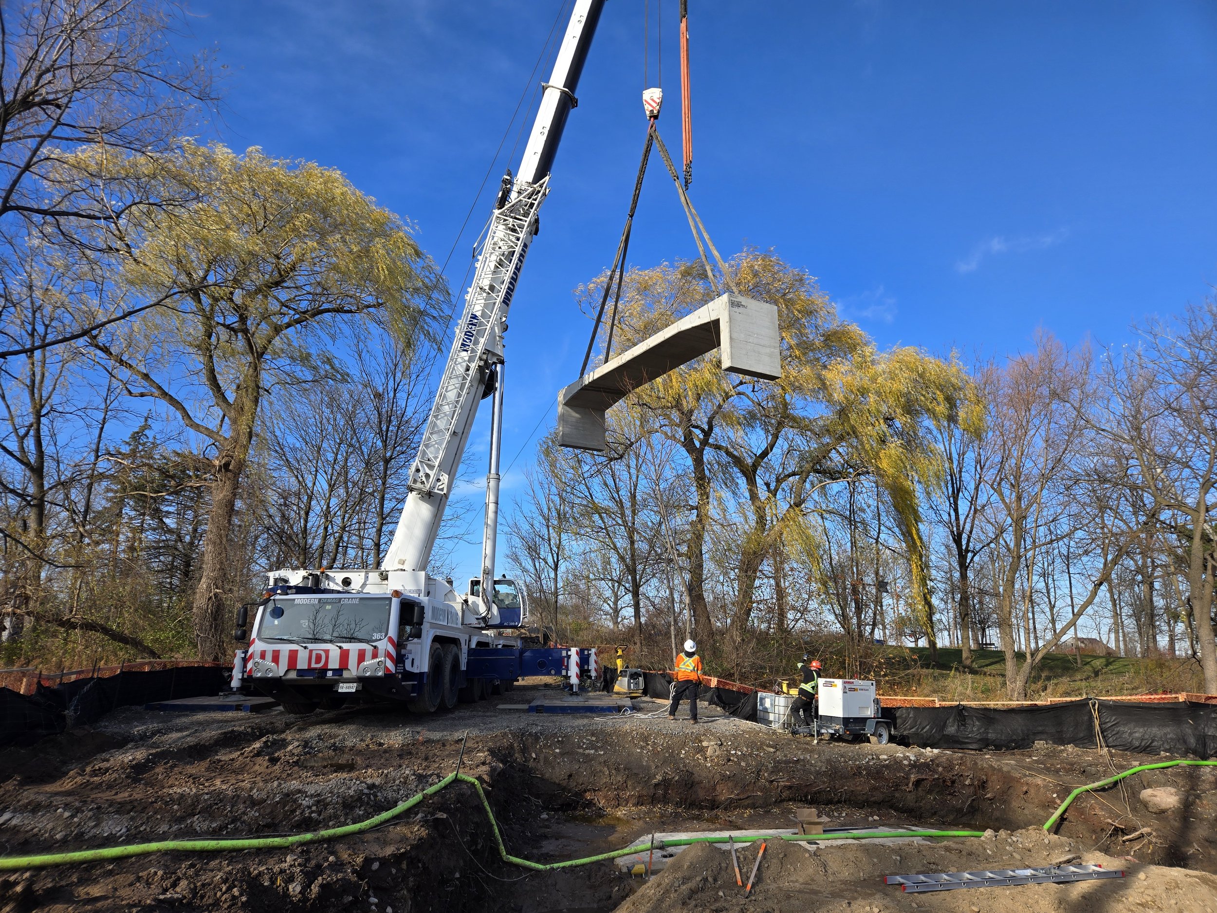 A construction site where workers are using a crane to lift and position a large concrete structure.