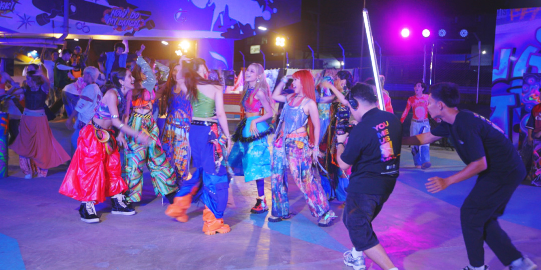 People dancing and having fun at a vibrant, colorful party or nightclub with neon lighting and graffiti-style artwork on the walls.