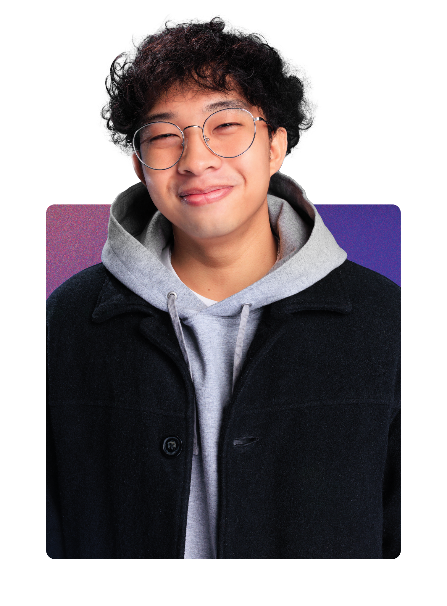 Young man with curly black hair, glasses, and a warm smile, wearing a gray hoodie and black coat, standing against a multicolored background.