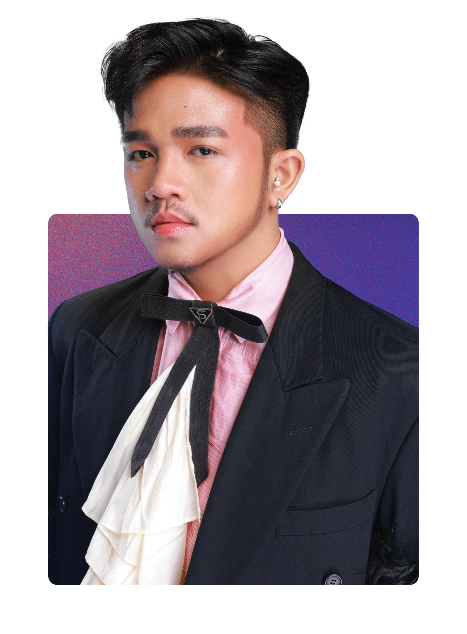 A man with black hair styled to the side, wearing a black blazer, pink shirt, with a black ribbon tied around his neck and a white ruffled detail. He has earrings and a serious expression, standing against a background with purple and pink tones.