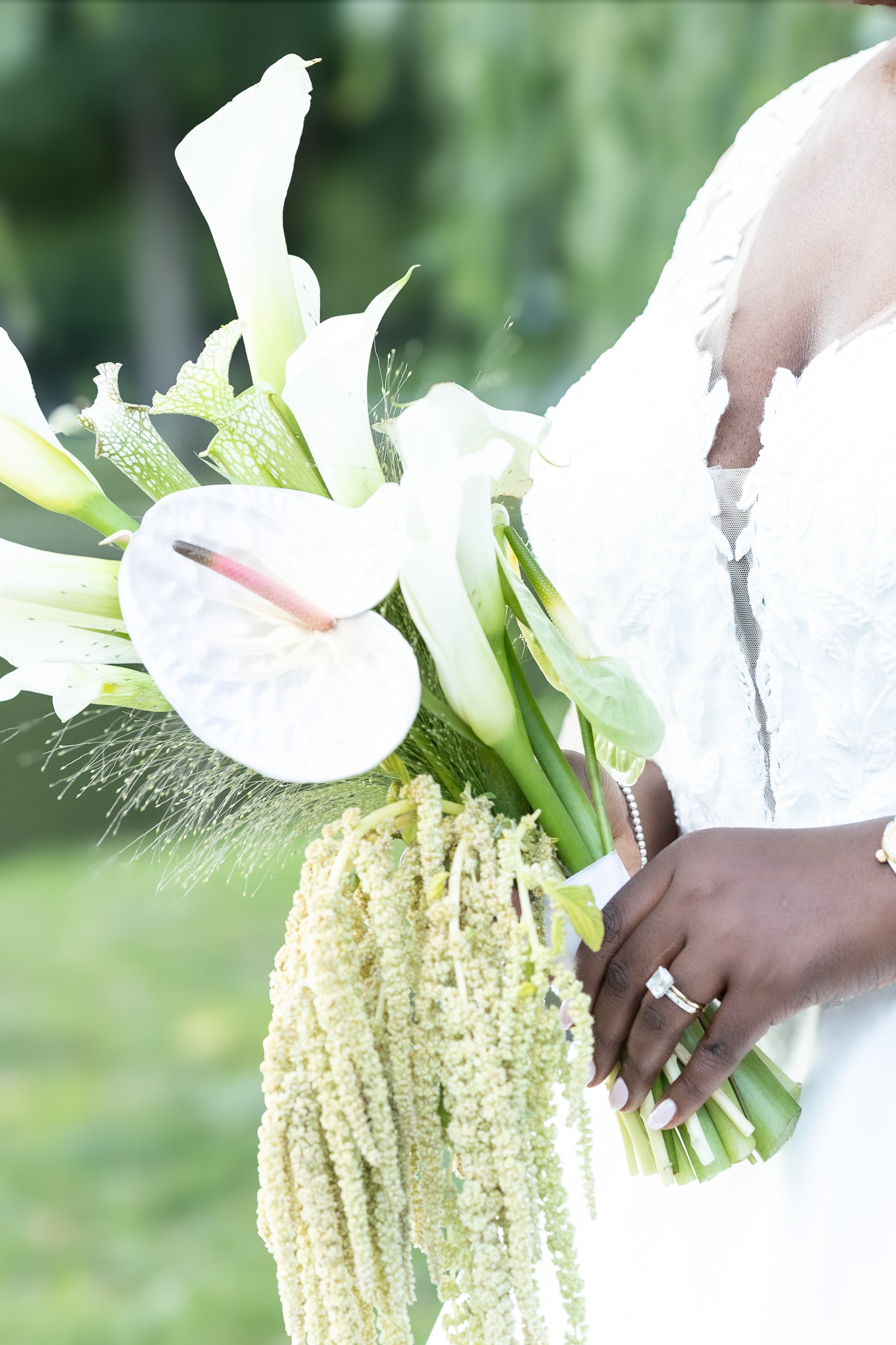 A woman in a white dress holding a bouquet of white flowers and greenery.