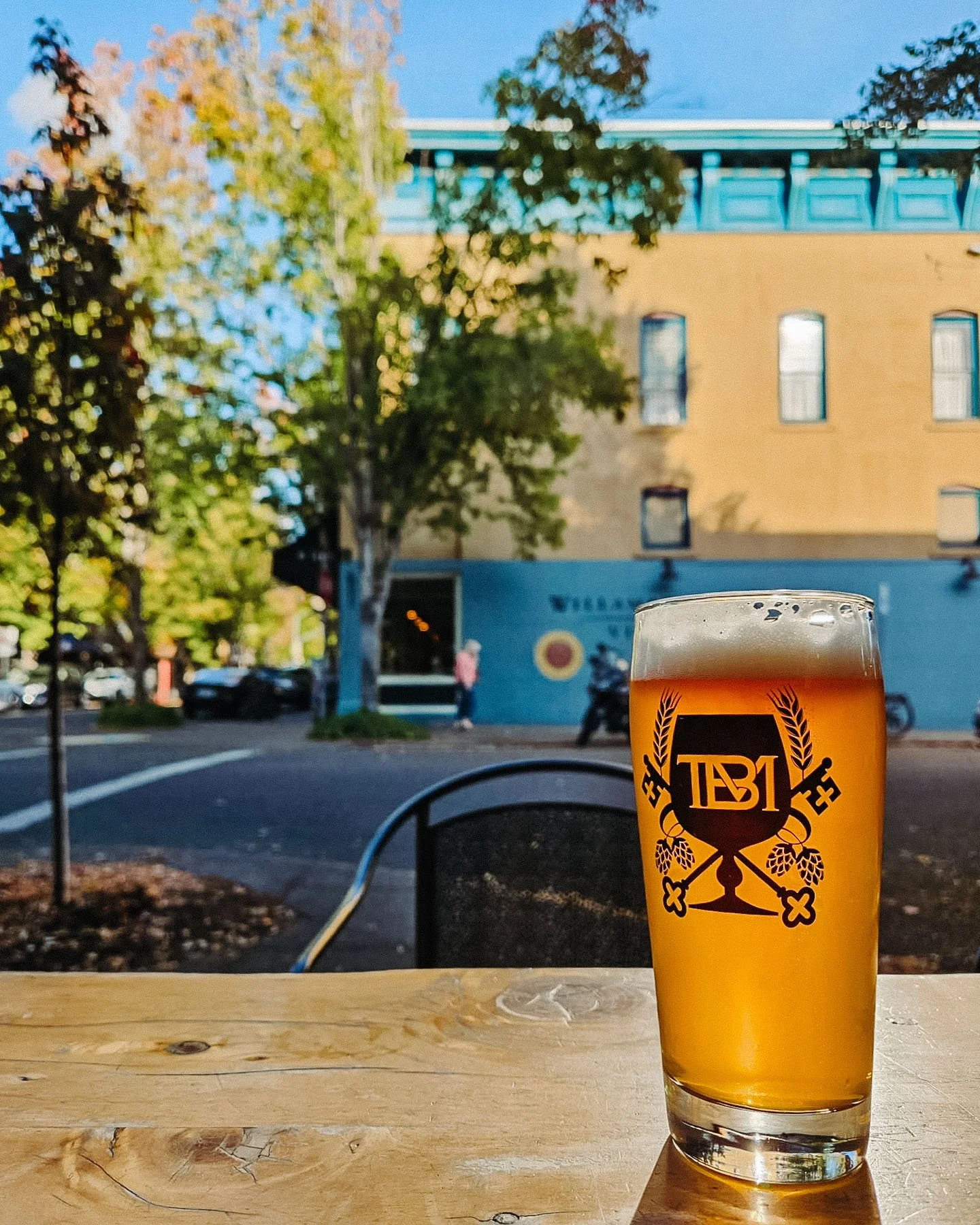 A pint of beer sitting on a table at the Bitter Monk craft beer bar in McMinnville, showing the outdoor patio that's open year round.