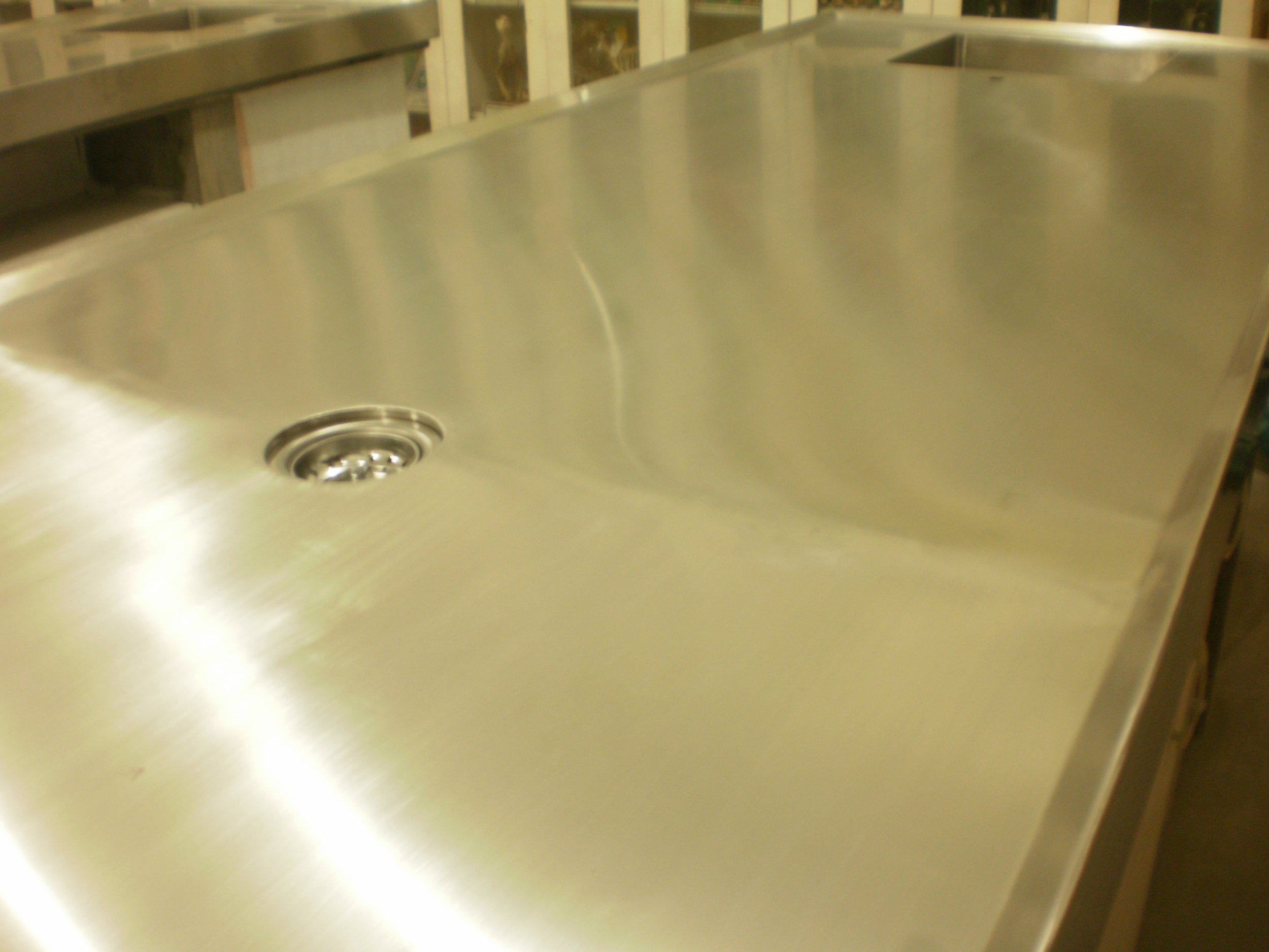 A stainless steel kitchen sink with a drain, part of a commercial kitchen counter.