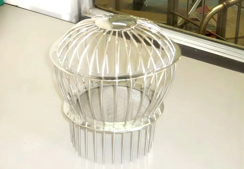A metal birdcage with a rounded top and vertical bars, placed on a white surface near a window.