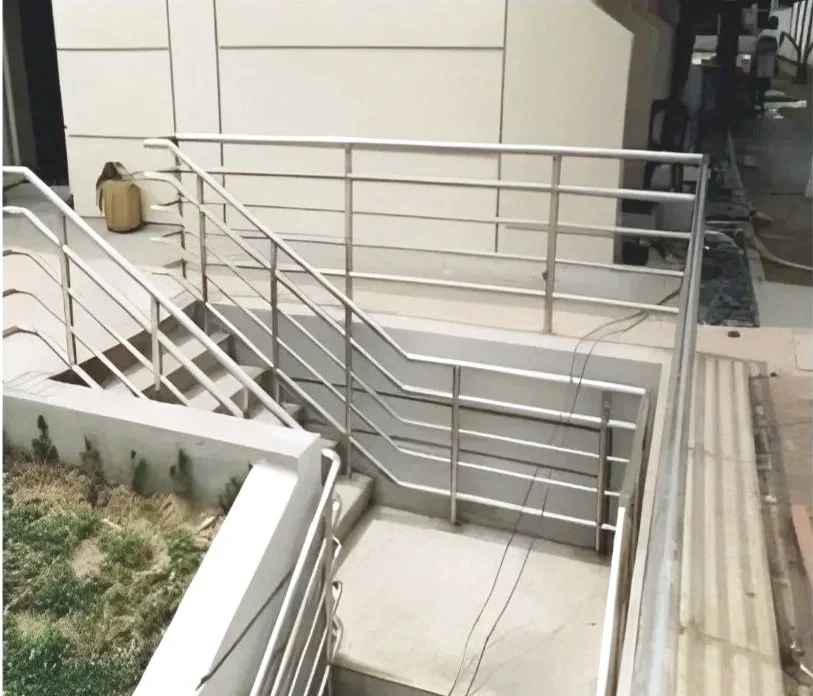 Staircase with metal railing outside a building, near a planter box and a beige exterior wall.