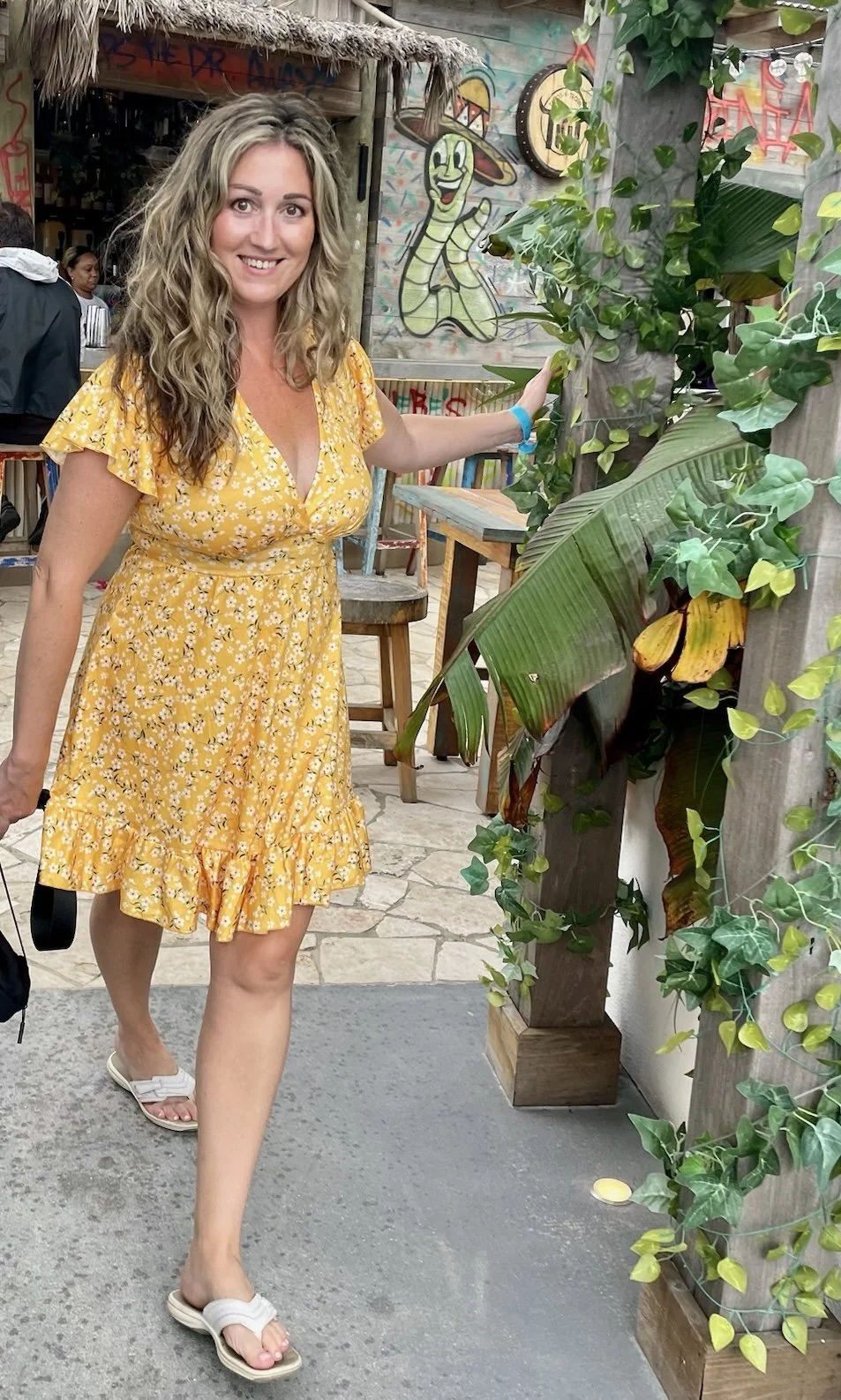 Erin, founder of EM travel, smiling in a yellow dress while traveling.