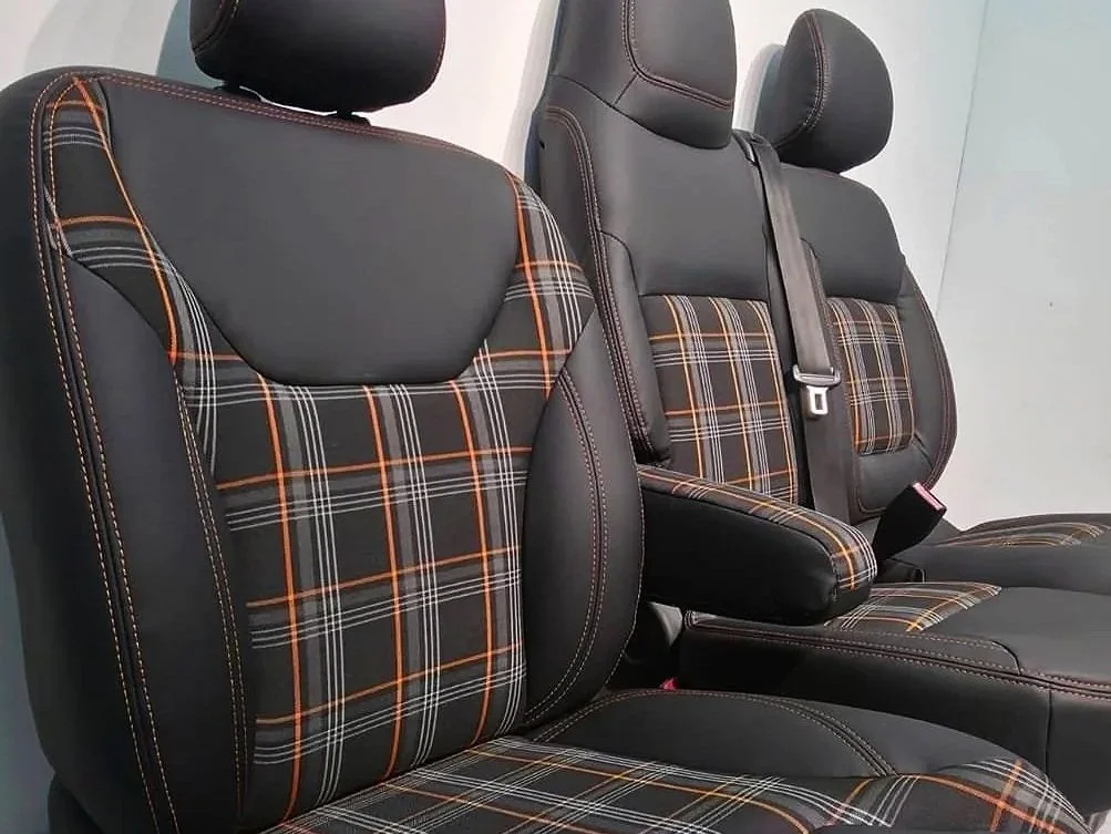 Car seats with plaid fabric and black leather accents, featuring adjustable headrests and seat belts.