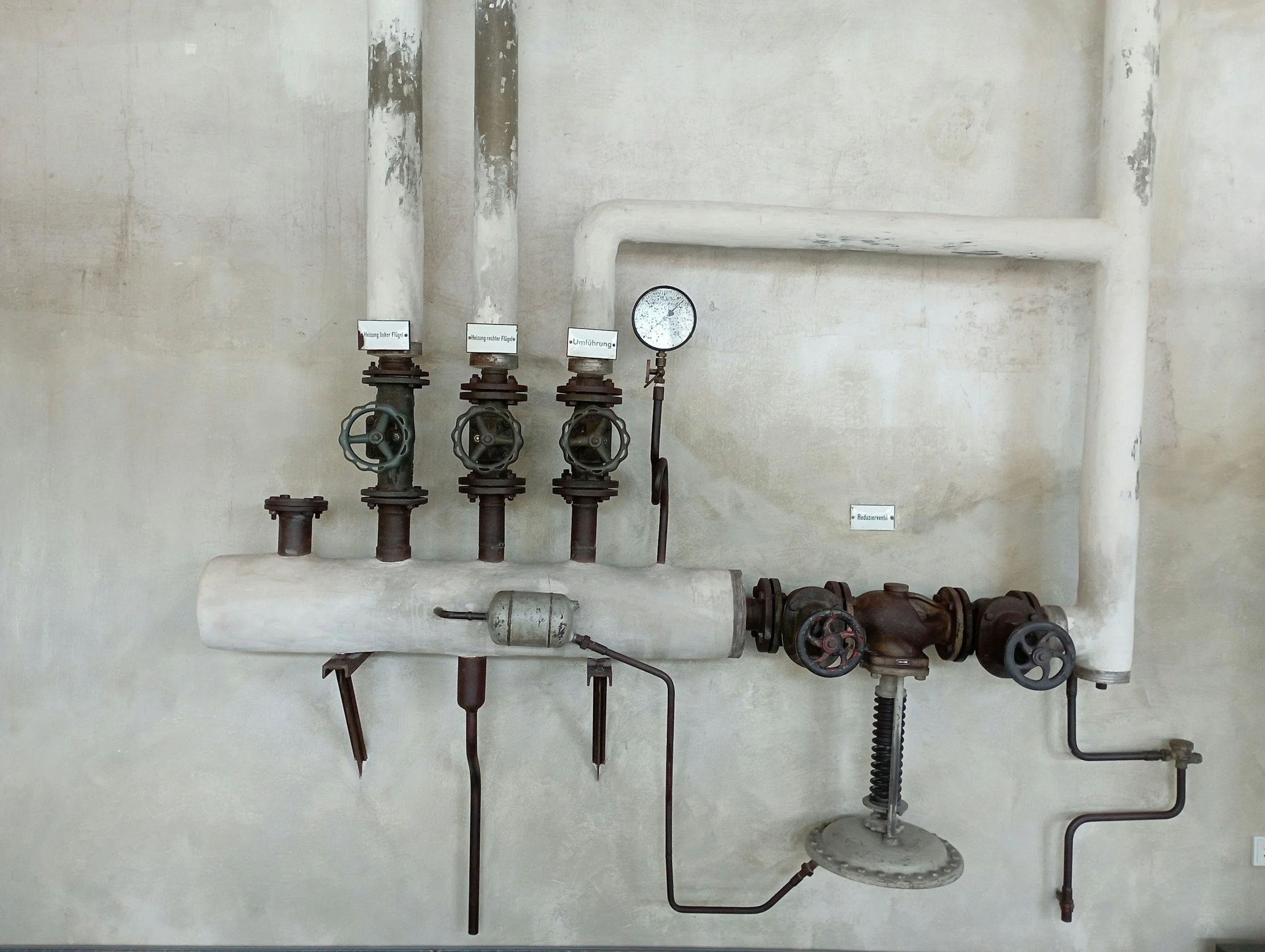 Industrial pipes and valves mounted on a concrete wall