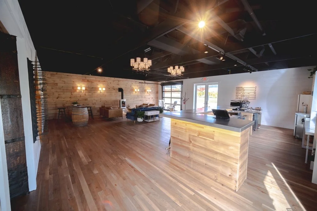 Spacious modern interior with wooden floor and walls, a kitchen island, seating area, and large windows letting in natural light.