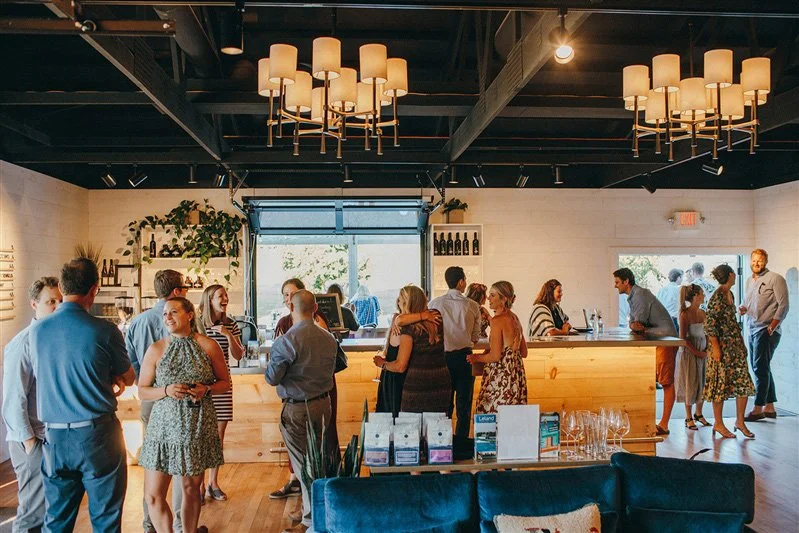 People socializing at a modern urban cafe or bar with a wooden counter and hanging lights.