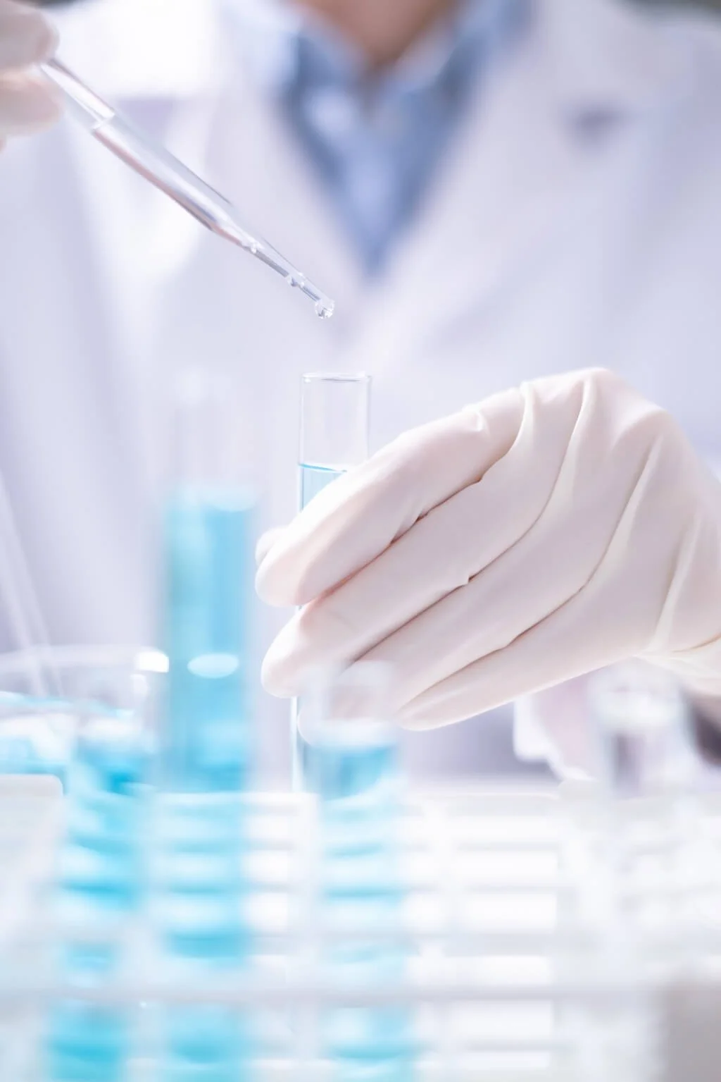 Scientist using a pipette to drop product into test tube in chemistry laboratory