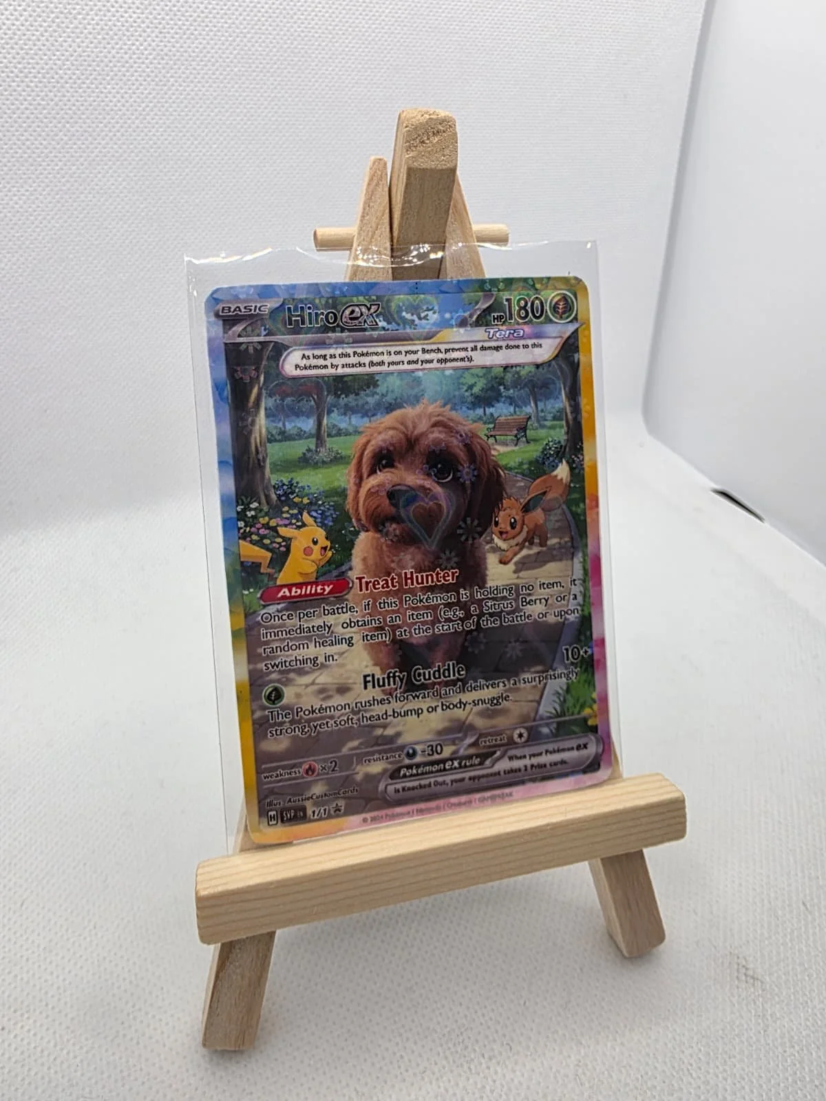 Pokemon card featuring a cute brown dog with a playful expression, set on a small wooden easel display.