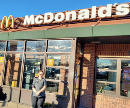 Person standing outside a McDonald's restaurant on a sunny day.