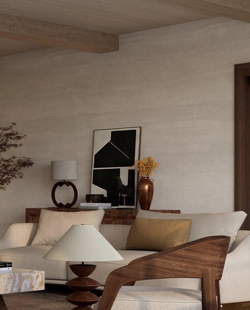 Interior living room with cream sofa, wooden armchair, side table with lamp, artwork, and decorative vase with yellow flowers.