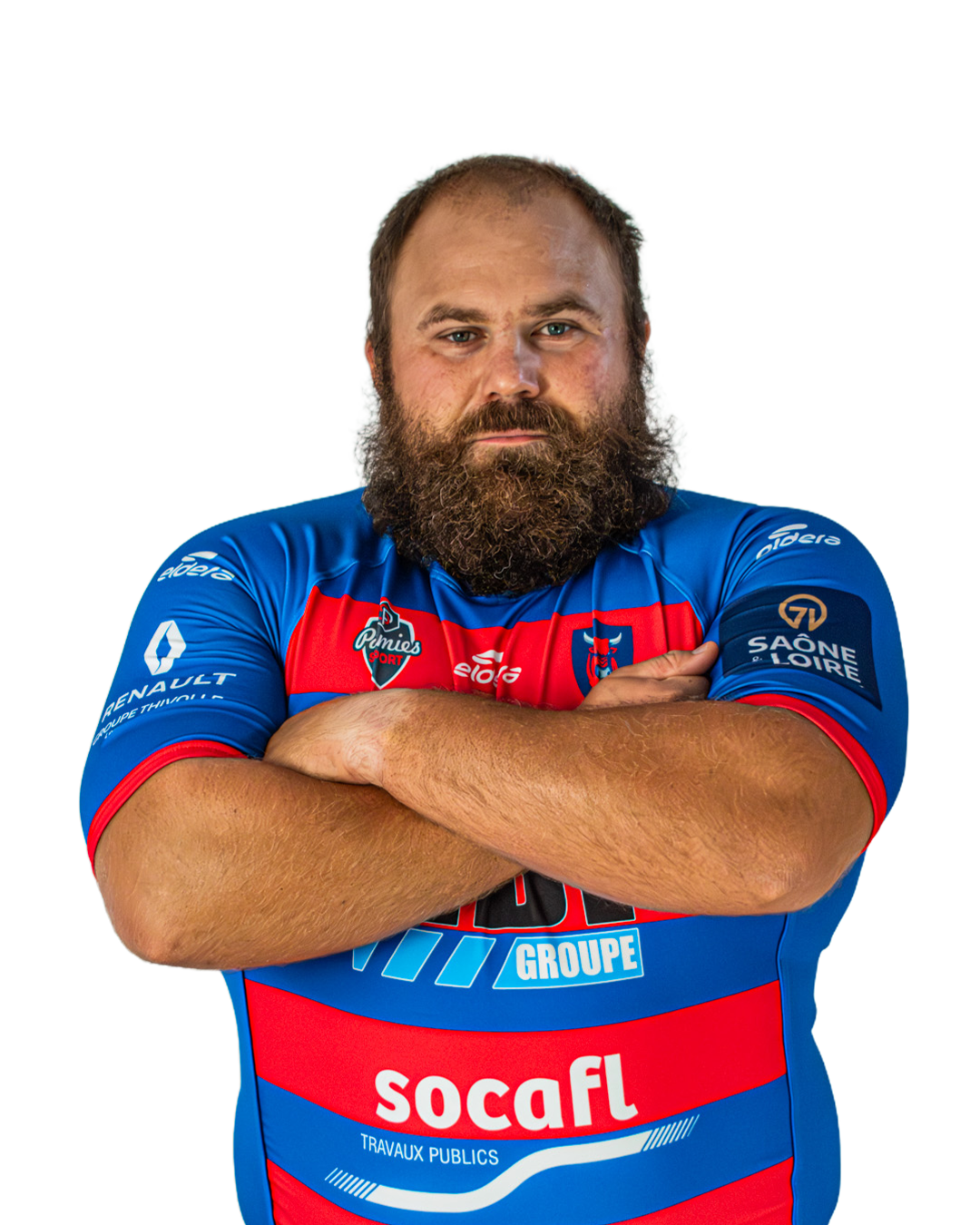 Un homme avec une barbe et un regard sérieux porte un maillot de rugby bleu avec des logos, bras croisés devant la poitrine.